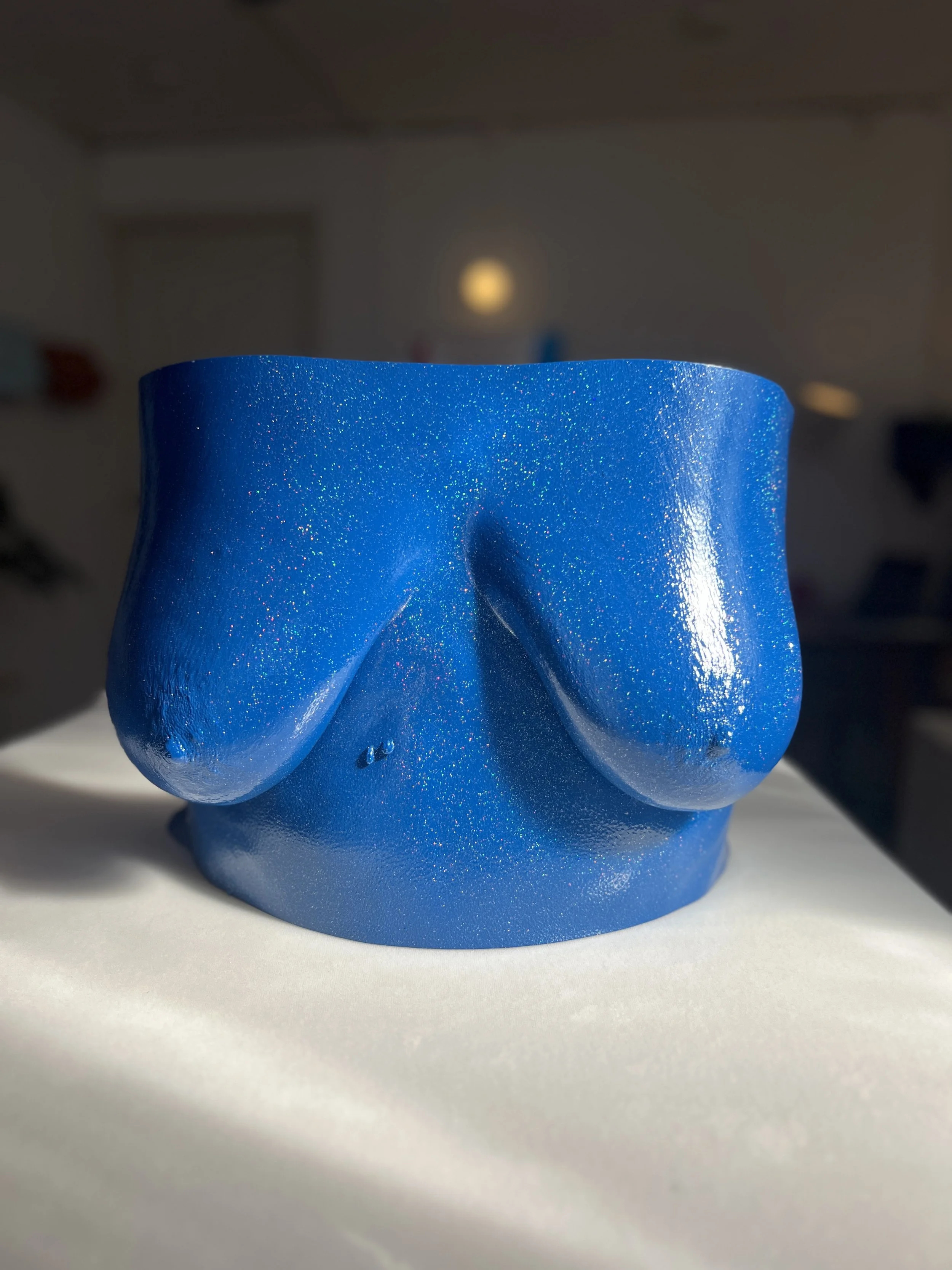 Donkerblauwe body casting sculptuur van een borstkas met borsten, kunstwerk van Venus in Vorm, handgemaakt van hars met glitters en glanzende afwerking, gefotografeerd in body casting atelier in de zon.