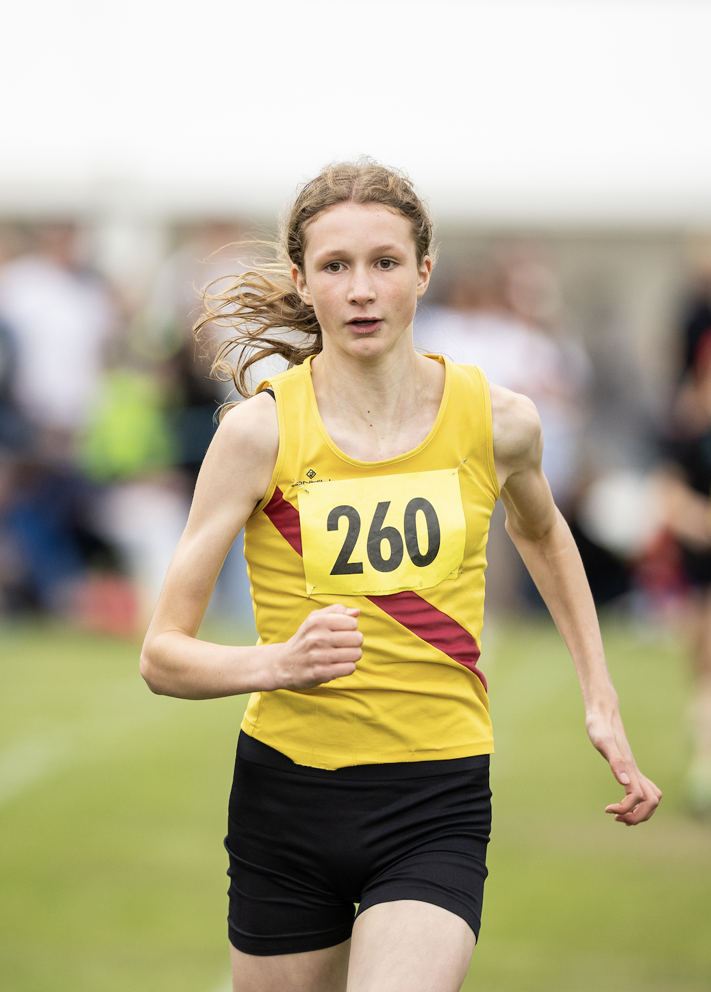 Cyclist wearing orange and blue biking outfit and helmet racing on a red bicycle.