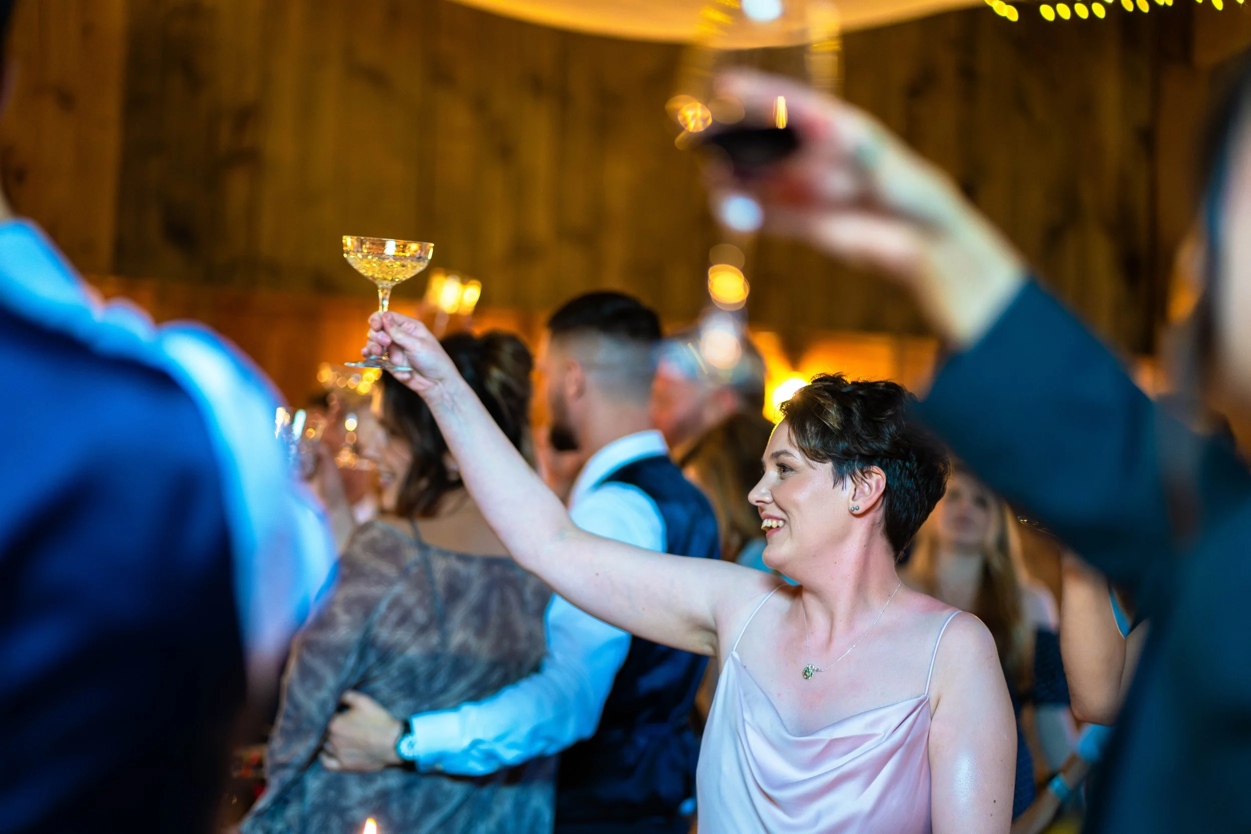 Bridesmaid raising a glass during speeches at Riverlands barn, a yorkshire countryside wedding venue