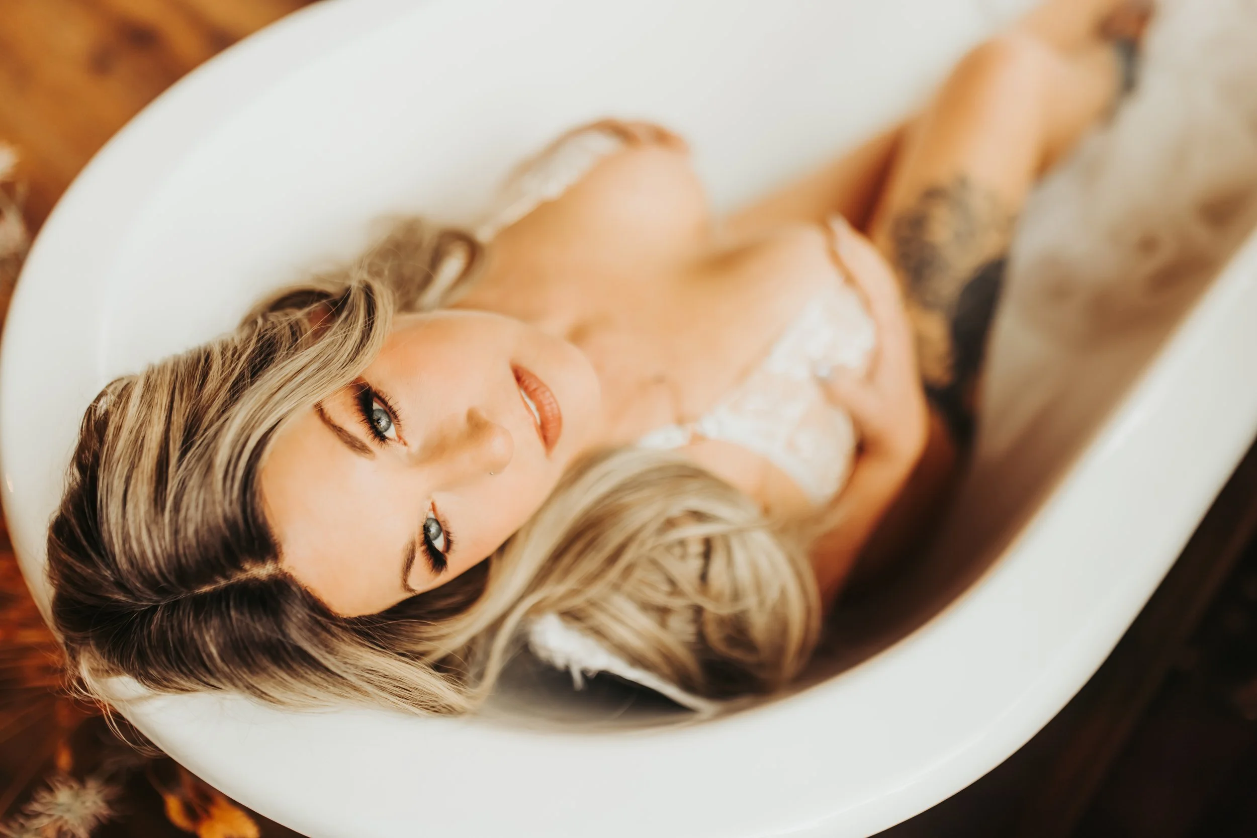 A woman laying in tub with lingerie and beautiful eye makeup