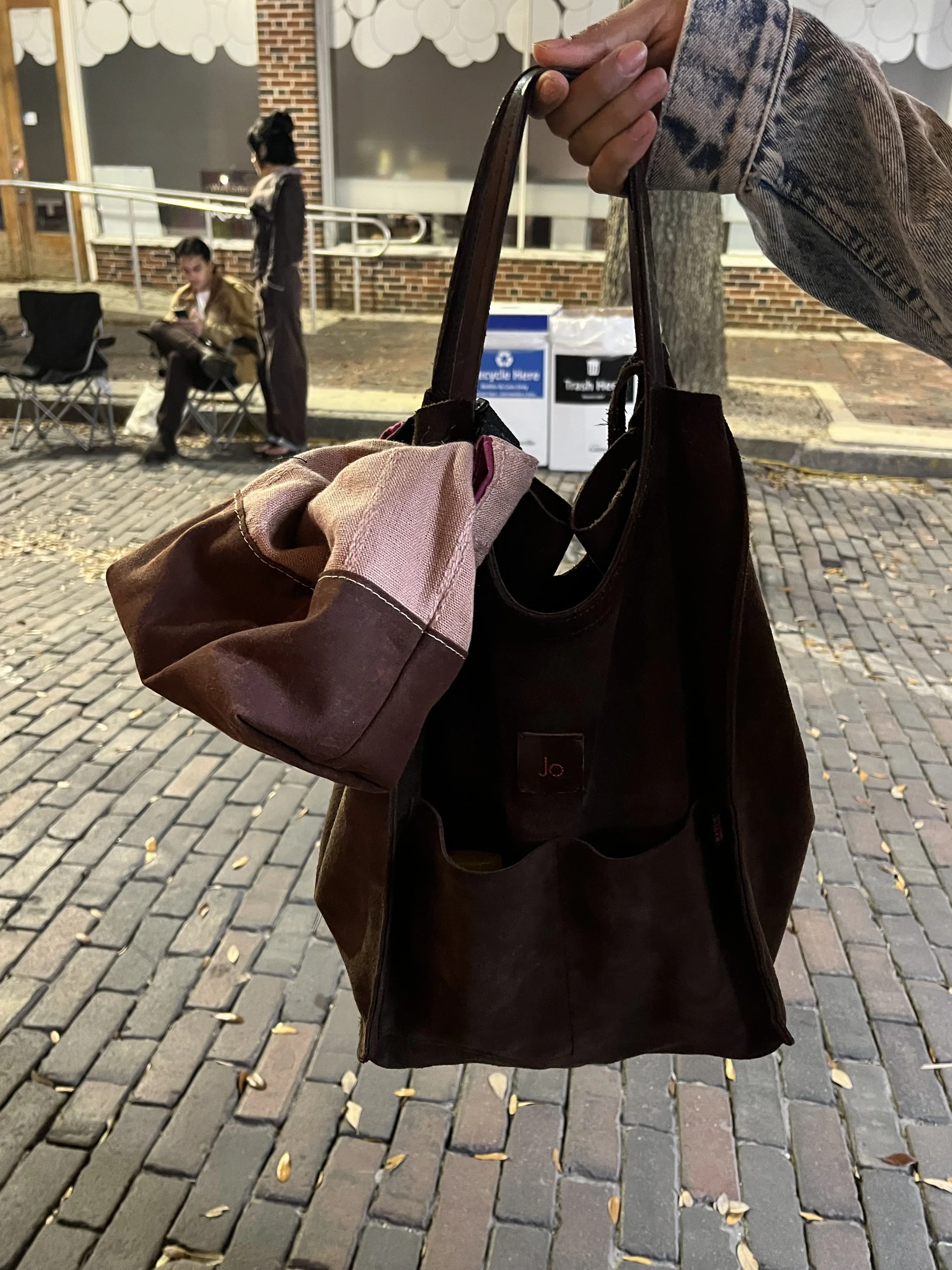 The rolltop clutch in pink and brown as seen attached to a customer's bag.