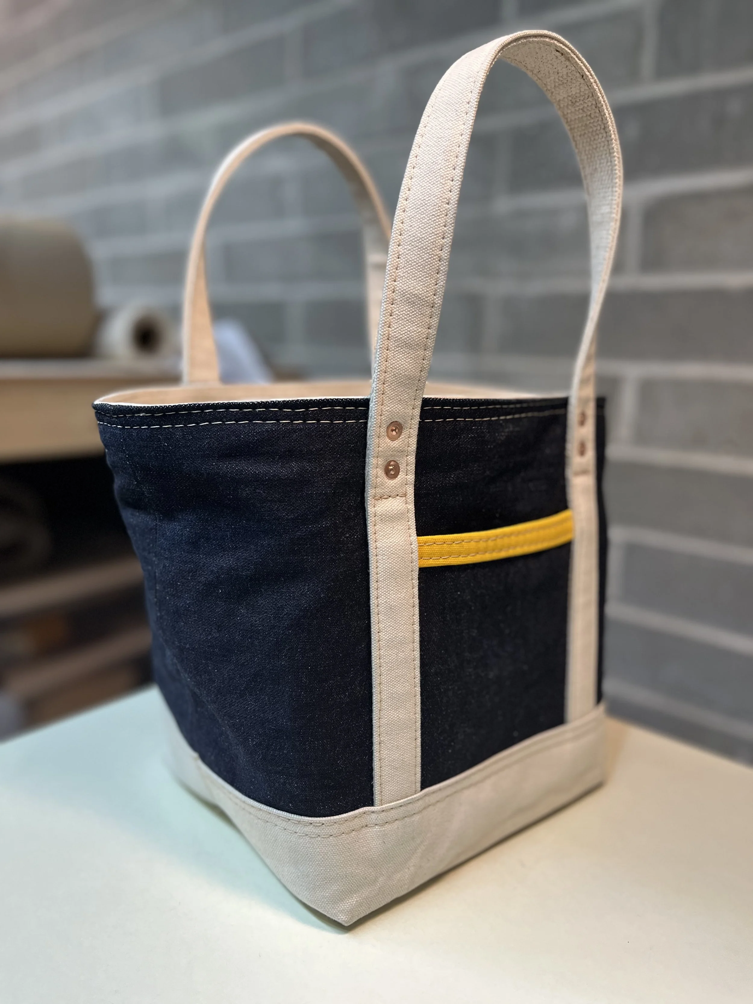 A small denim and natural canvas tote sits on a table top.