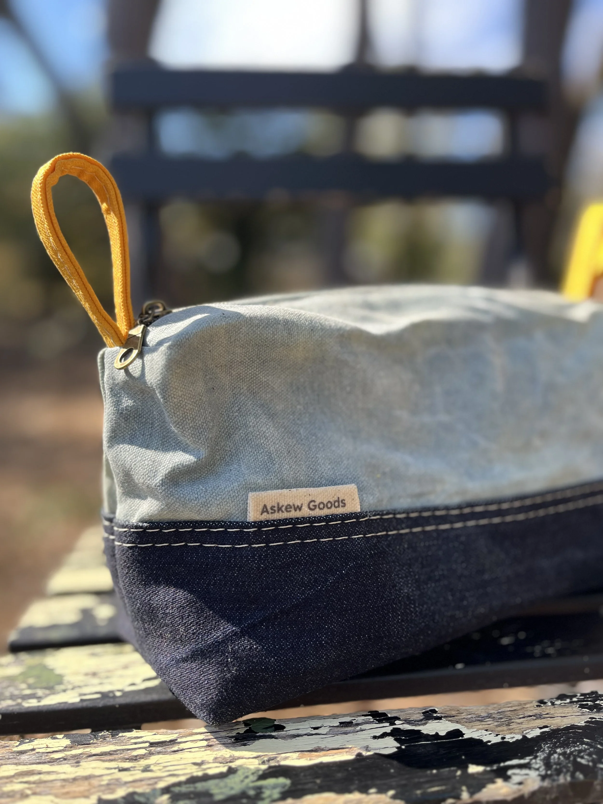 Indigo, raw denim, and mattress ticking carryall with yellow waxed canvas zipper loops.