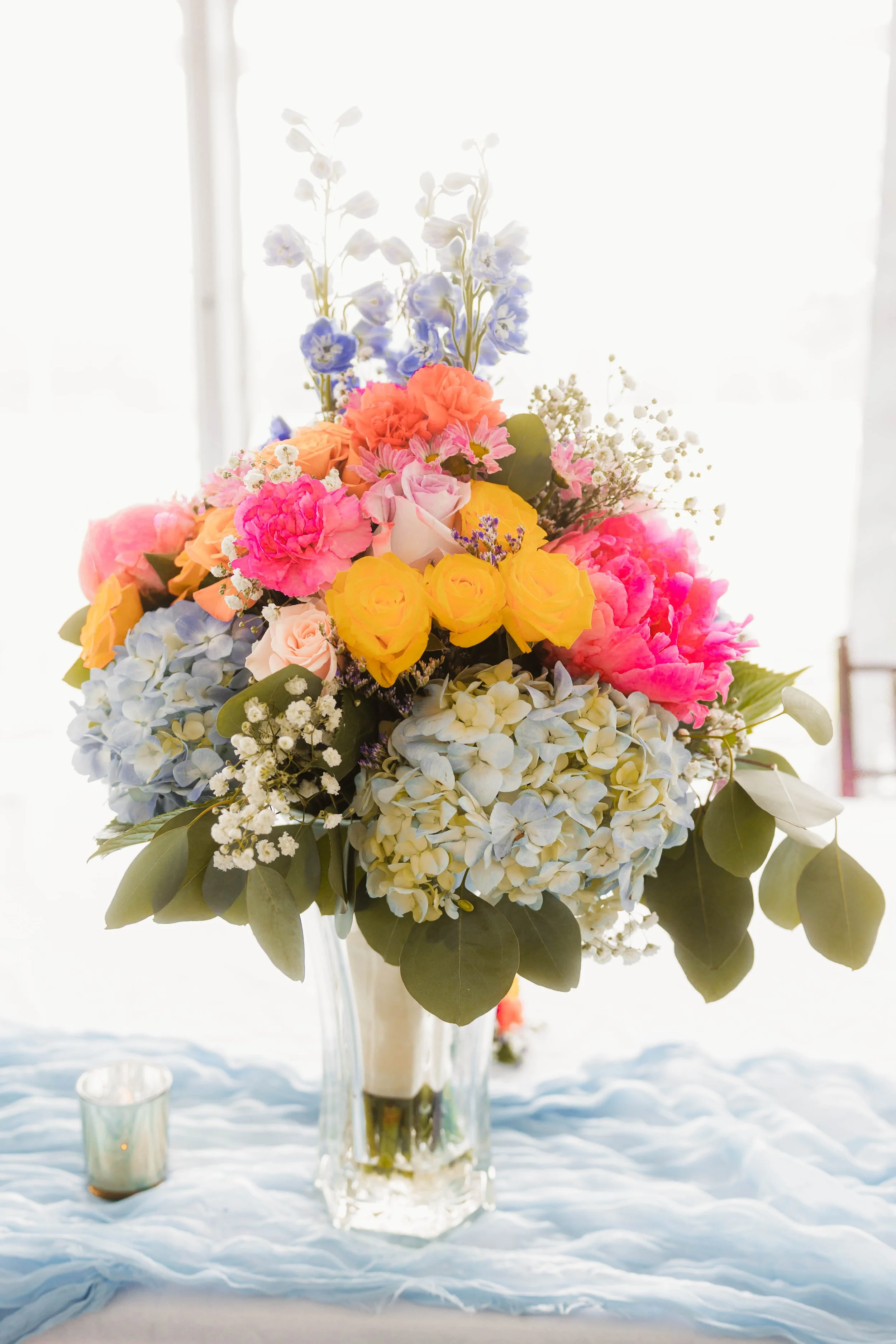 Colorful bouquet of flowers in a glass vase on a table, with a softly lit background.