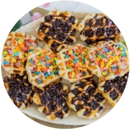 Waffles topped with colorful cereal and chocolate on a tray.