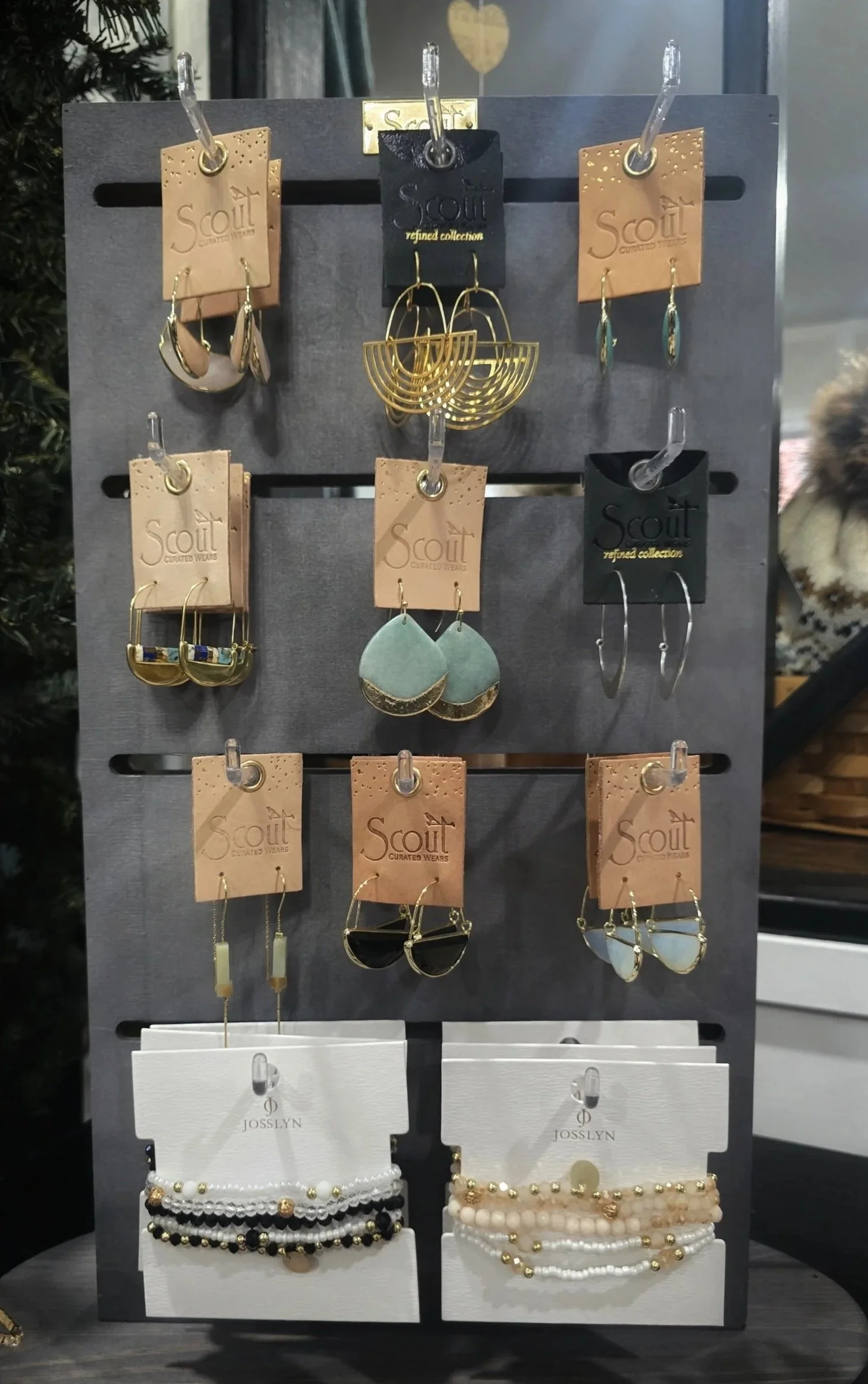 Display stand with various earrings and bracelets, featuring gold, silver, and pastel-colored accessories.