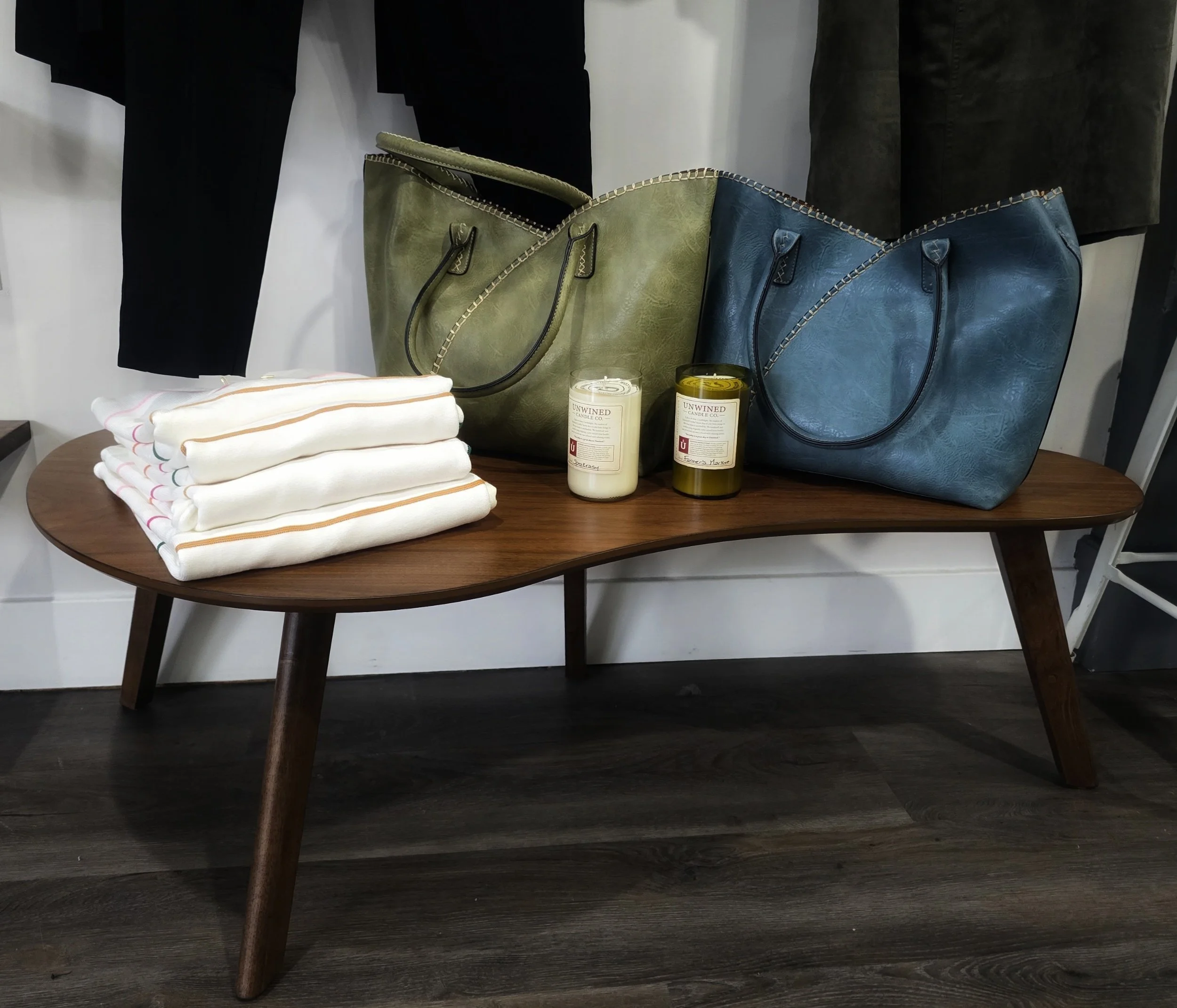 Wooden bench with two leather handbags and candles on top.