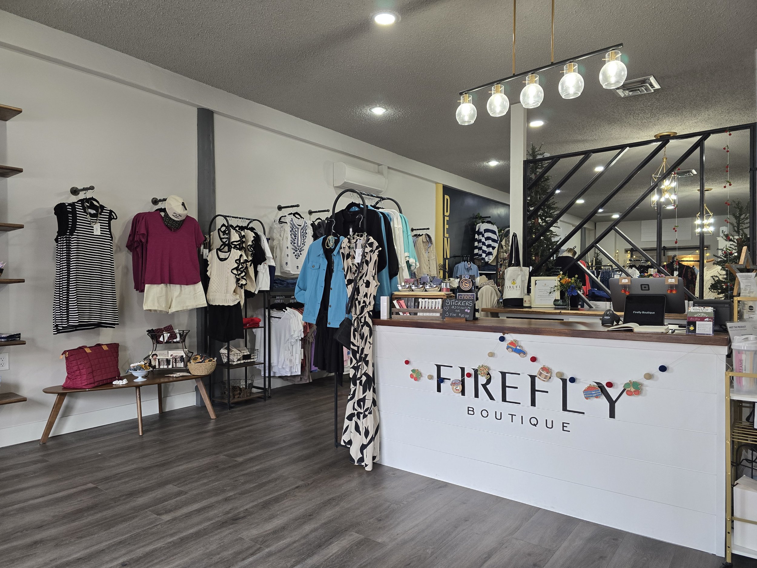 Interior view of a boutique store with clothing displays, accessories, and a checkout counter