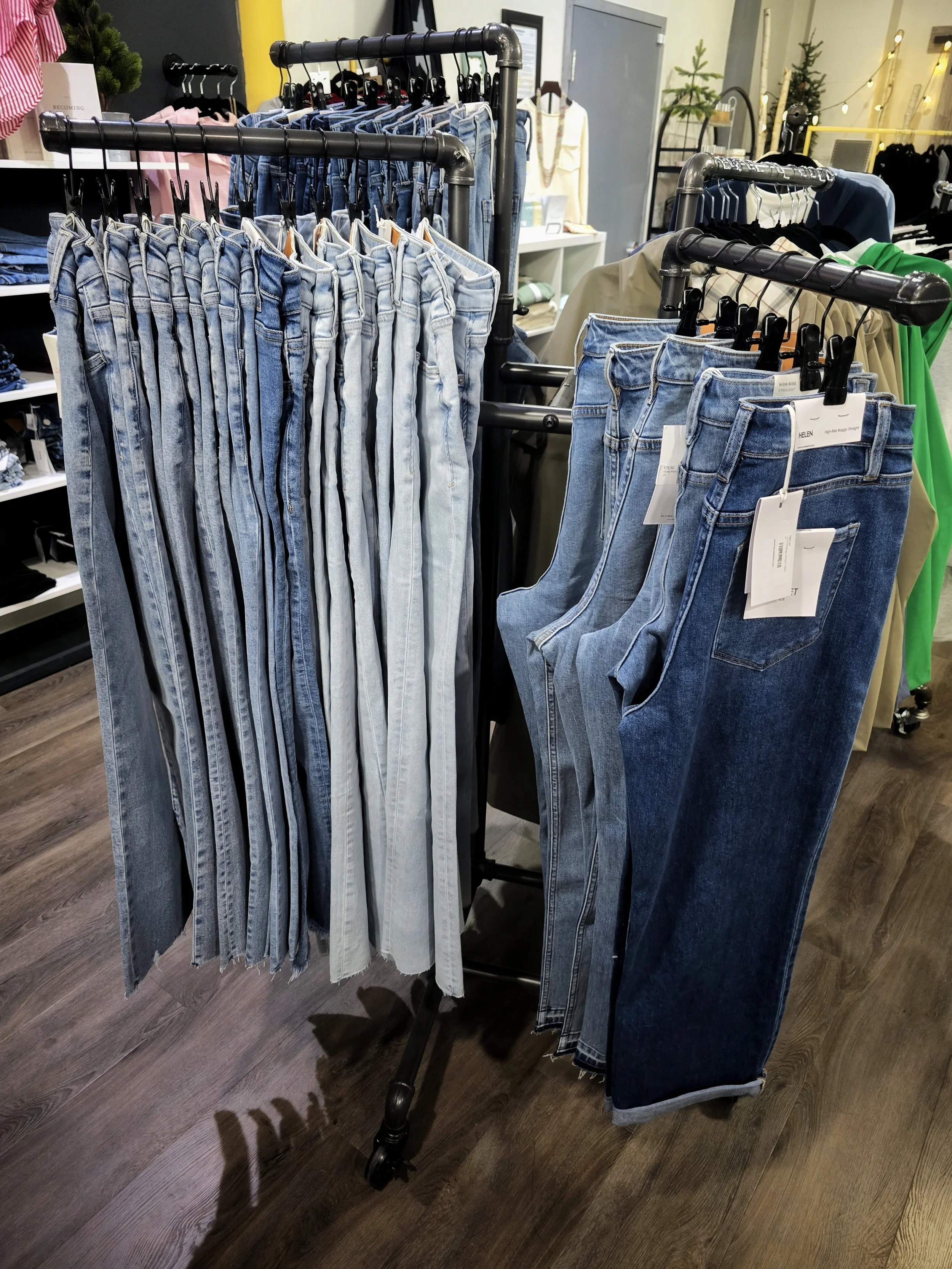 Display of various pairs of blue jeans on black clothing racks in a retail store.