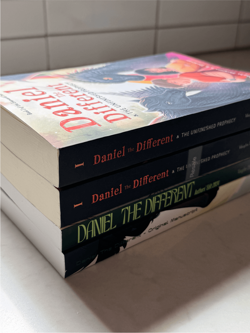 Photo of stack of all Daniel the Different books from original manuscript to final production