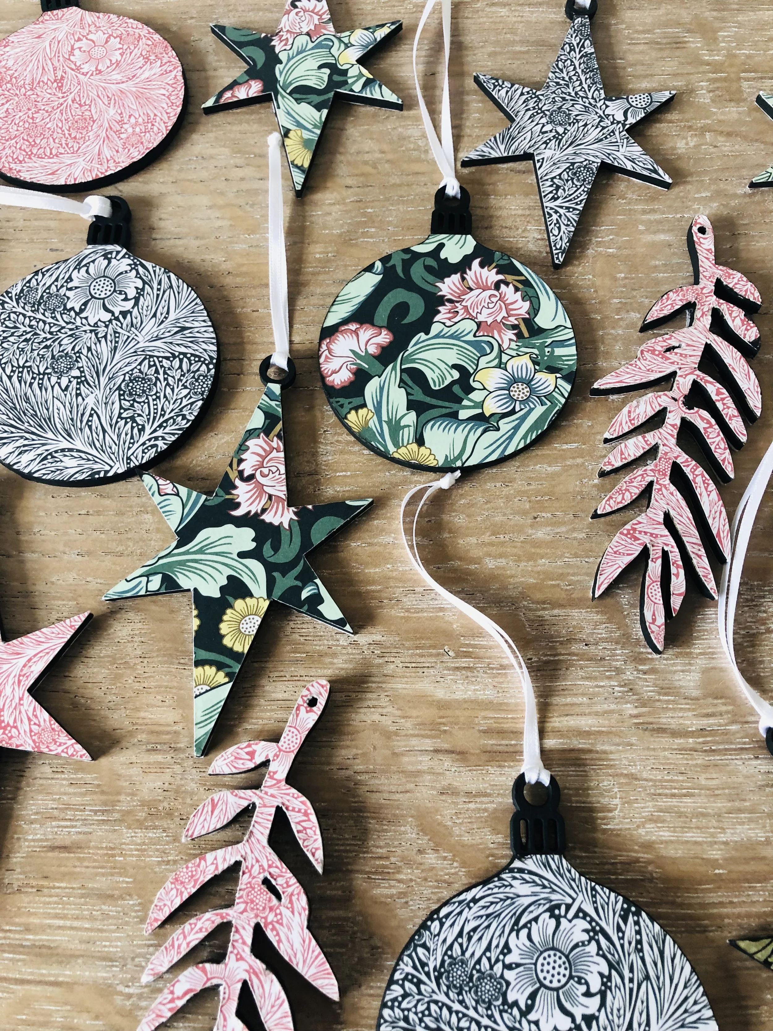 Decorative paper ornaments in floral, star, round, and leaf shapes with colorful and black-and-white patterns, lying on a wooden surface.