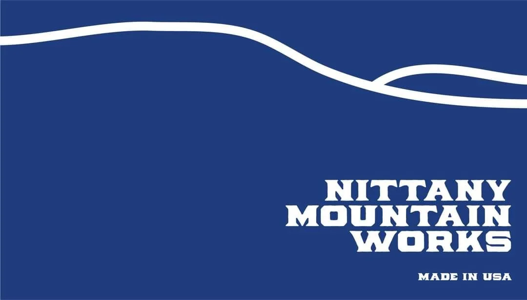 Nittany Mountain Works logo on a blue background with white text and white wavy lines.
