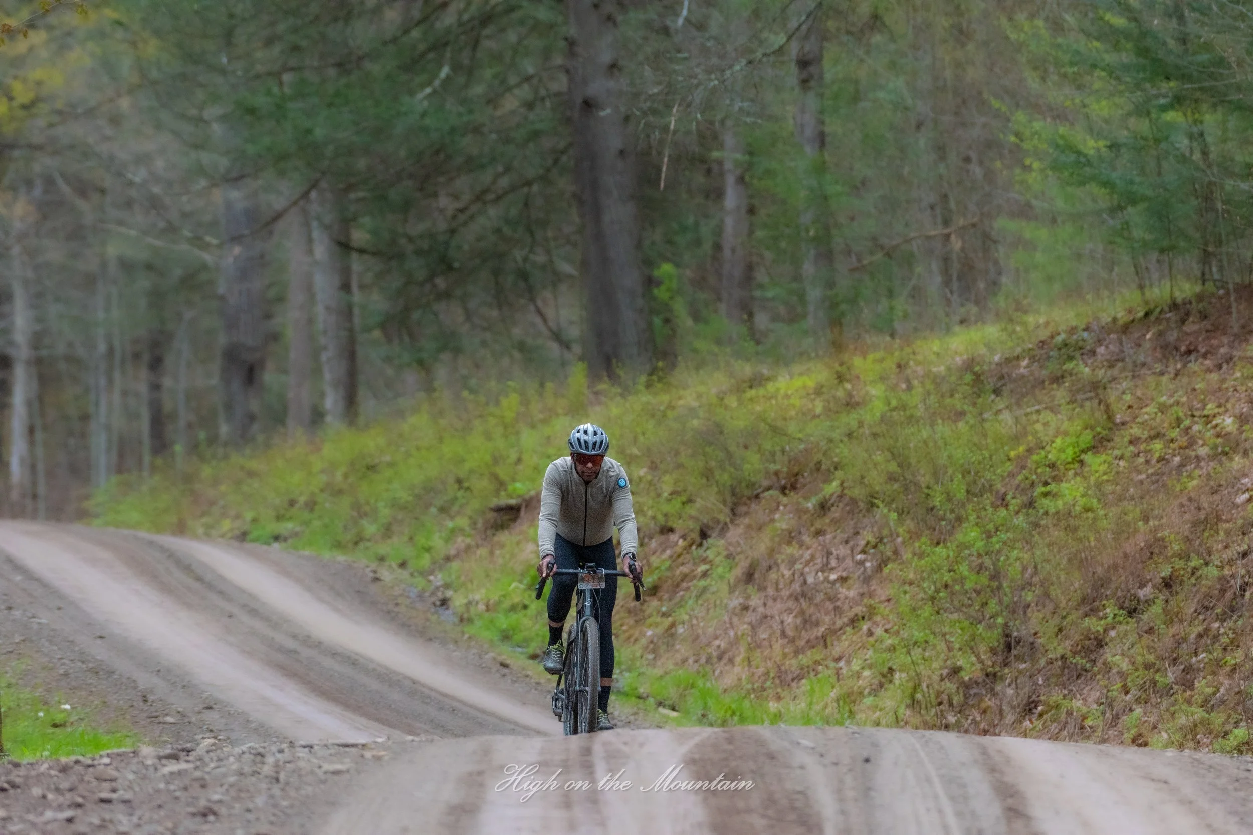A person riding a mountain bike on a dirt trail through a wooded forest.