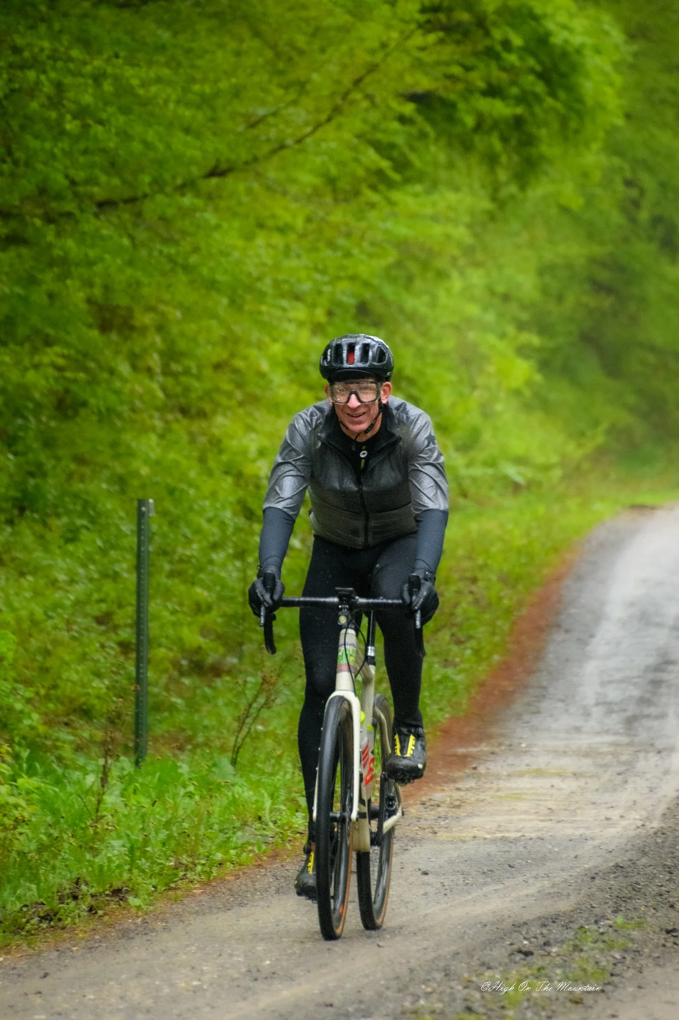 A person riding a bicycle on a forested path with green trees and foliage on both sides.