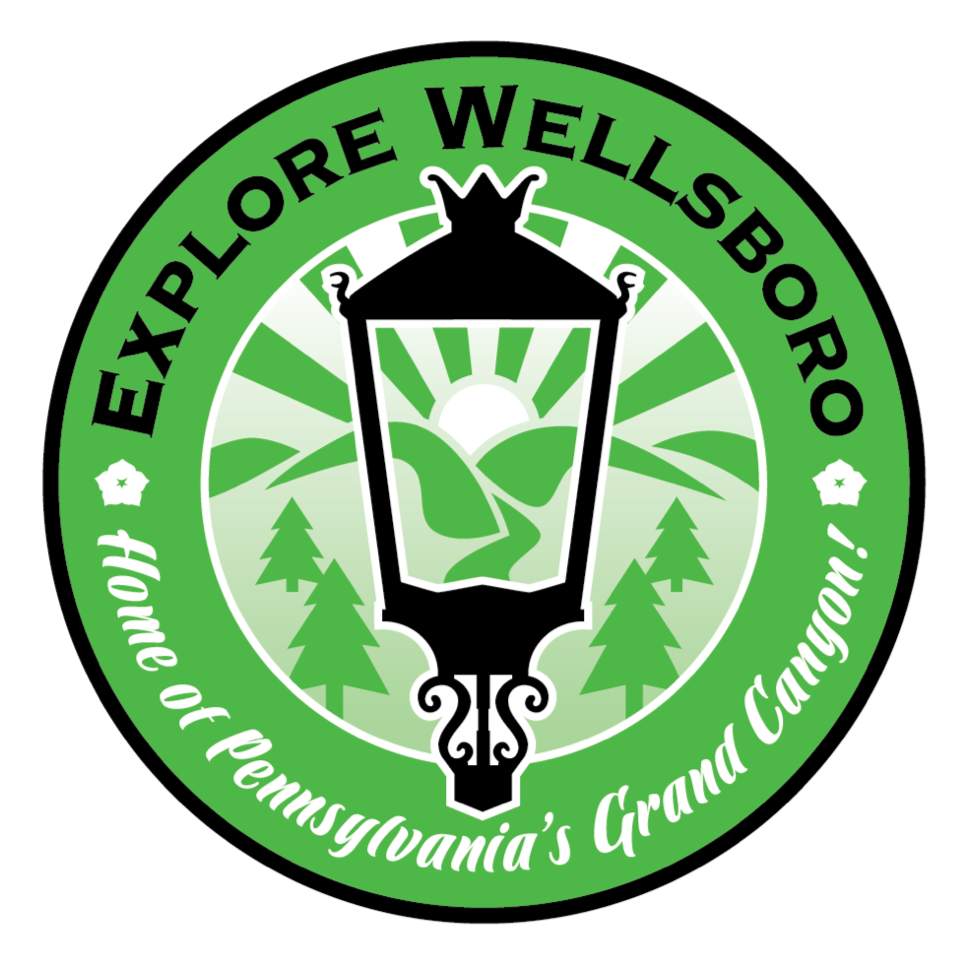 Explore Wellsboro logo featuring a green and white circular design with a central lantern, sun, hills, and trees, surrounded by text 'Explore Wellsboro' and 'Home of Pennsylvania's Grand Canyon.'