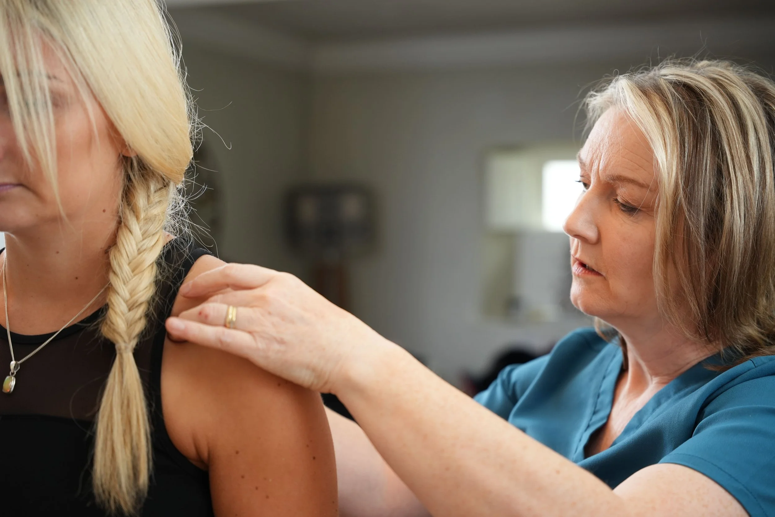 Osteopath Cathy Hearne examining the shoulder of a woman