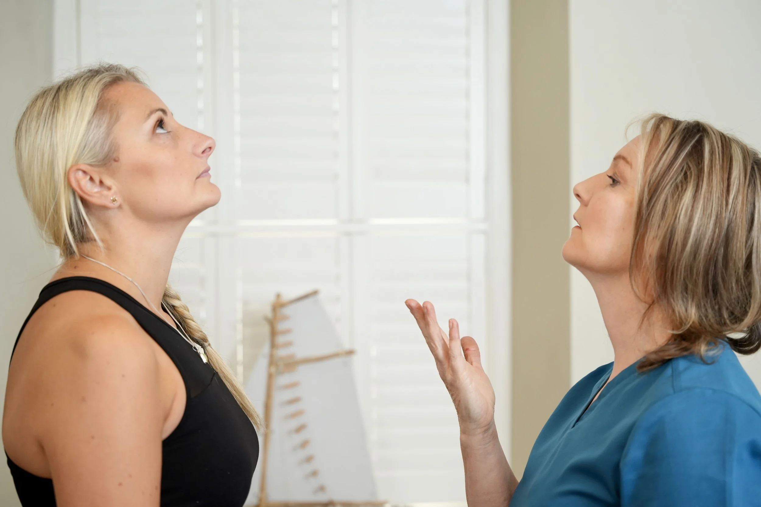 A lady together with Cathy Hearne, Osteopath. Cathy is showing the lady a neck movement and they are both looking upwards.
