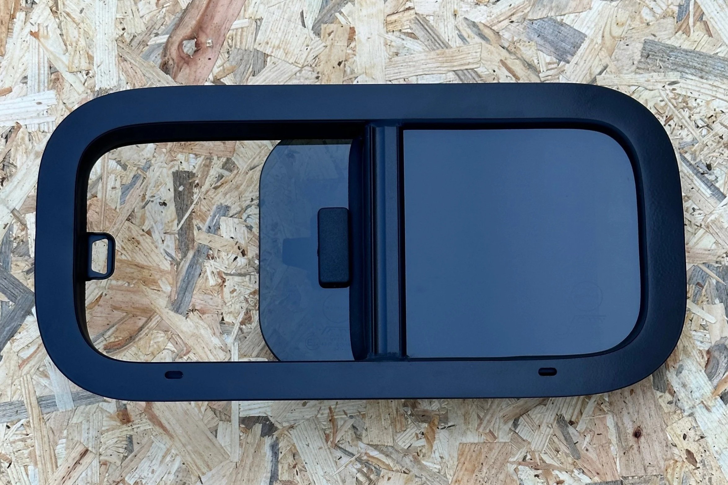 A black, oval-shaped object with a sliding cover, placed on a wooden surface.