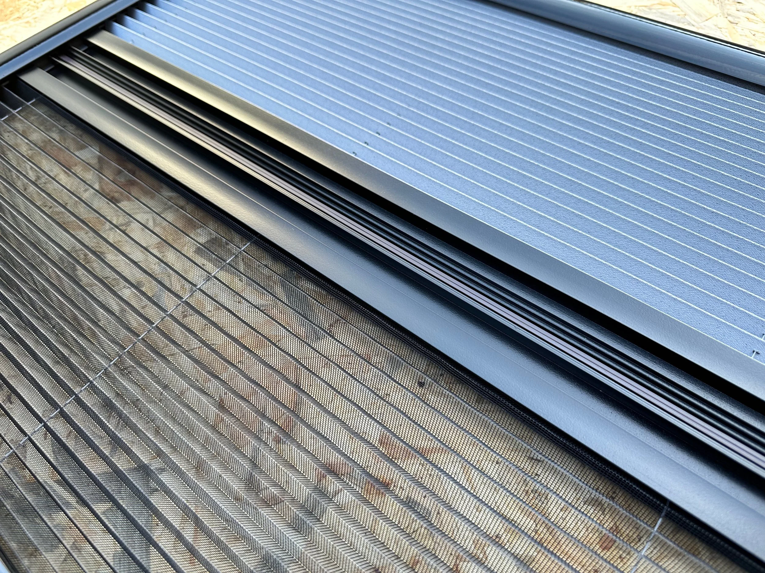 Close-up of a sliding screen door and window screens, showing the metal frames and mesh.