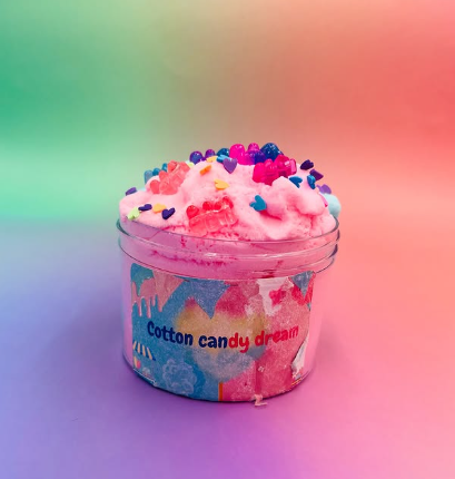 Cotton candy in a clear cup with colorful sprinkles, against a pastel rainbow background.