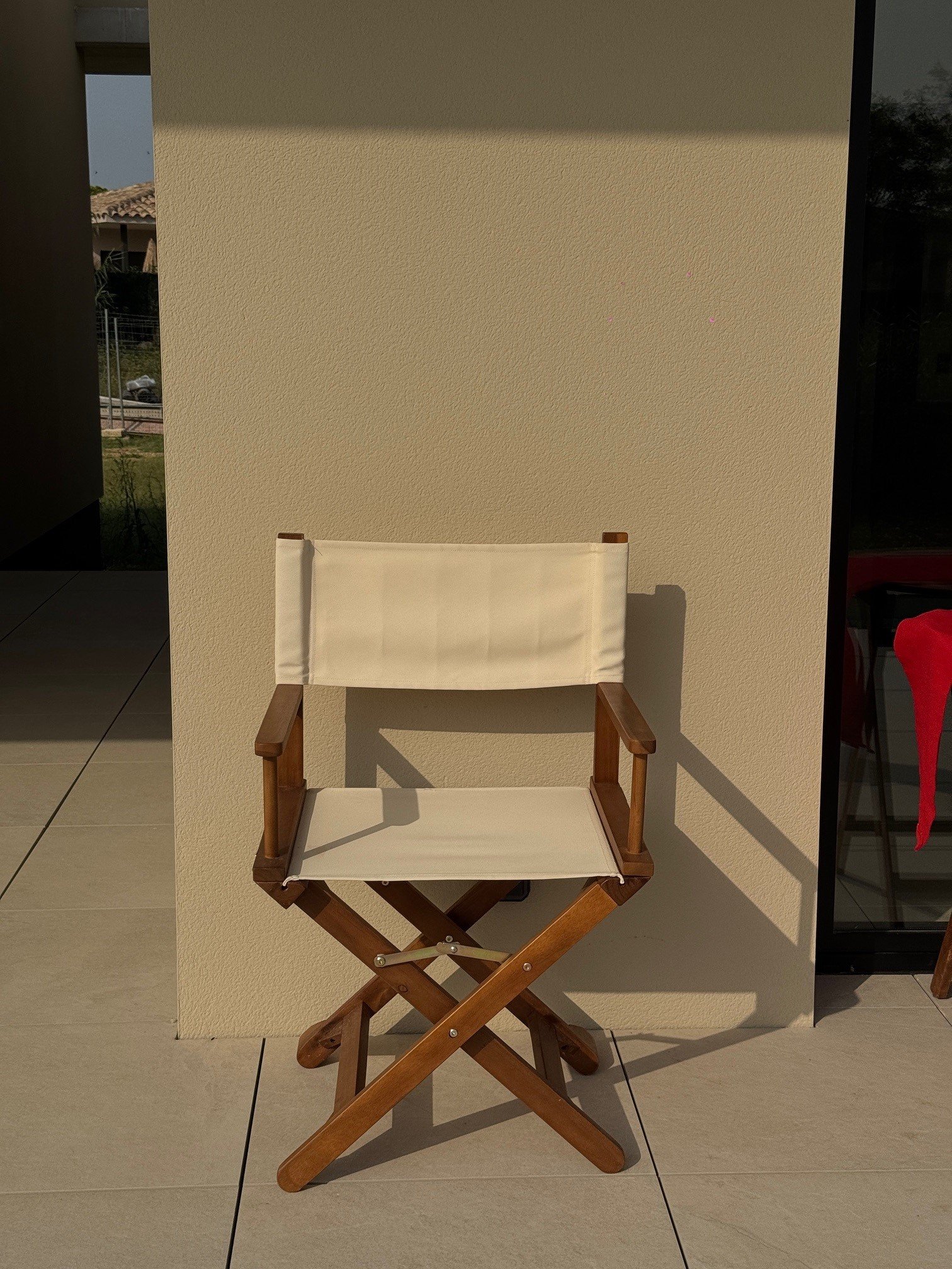 Modern living room with large windows, white sofas, wooden floor, indoor plants, artwork on walls, and natural light.