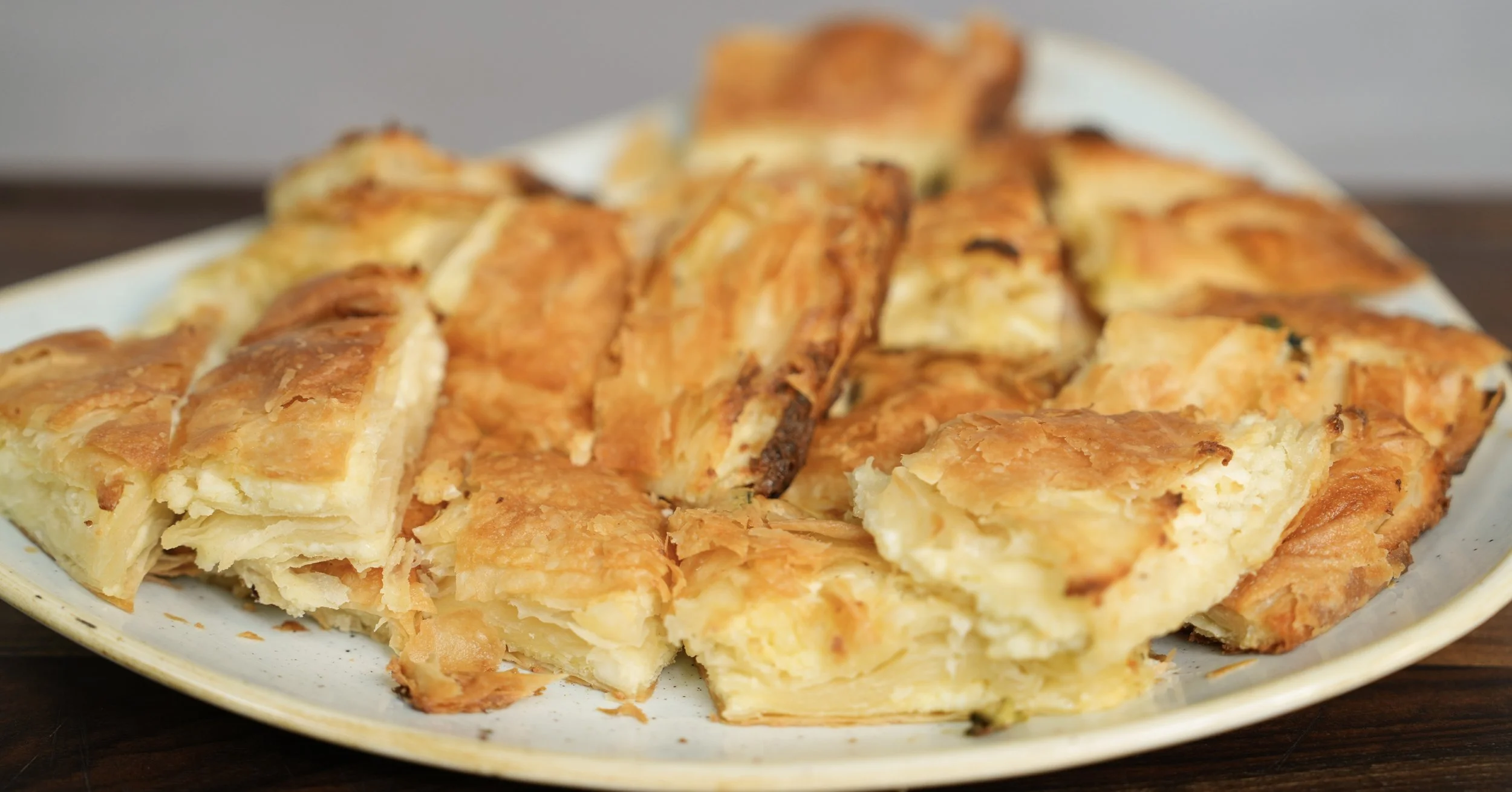 Plate of golden-brown, flaky pastry squares on a ceramic dish.