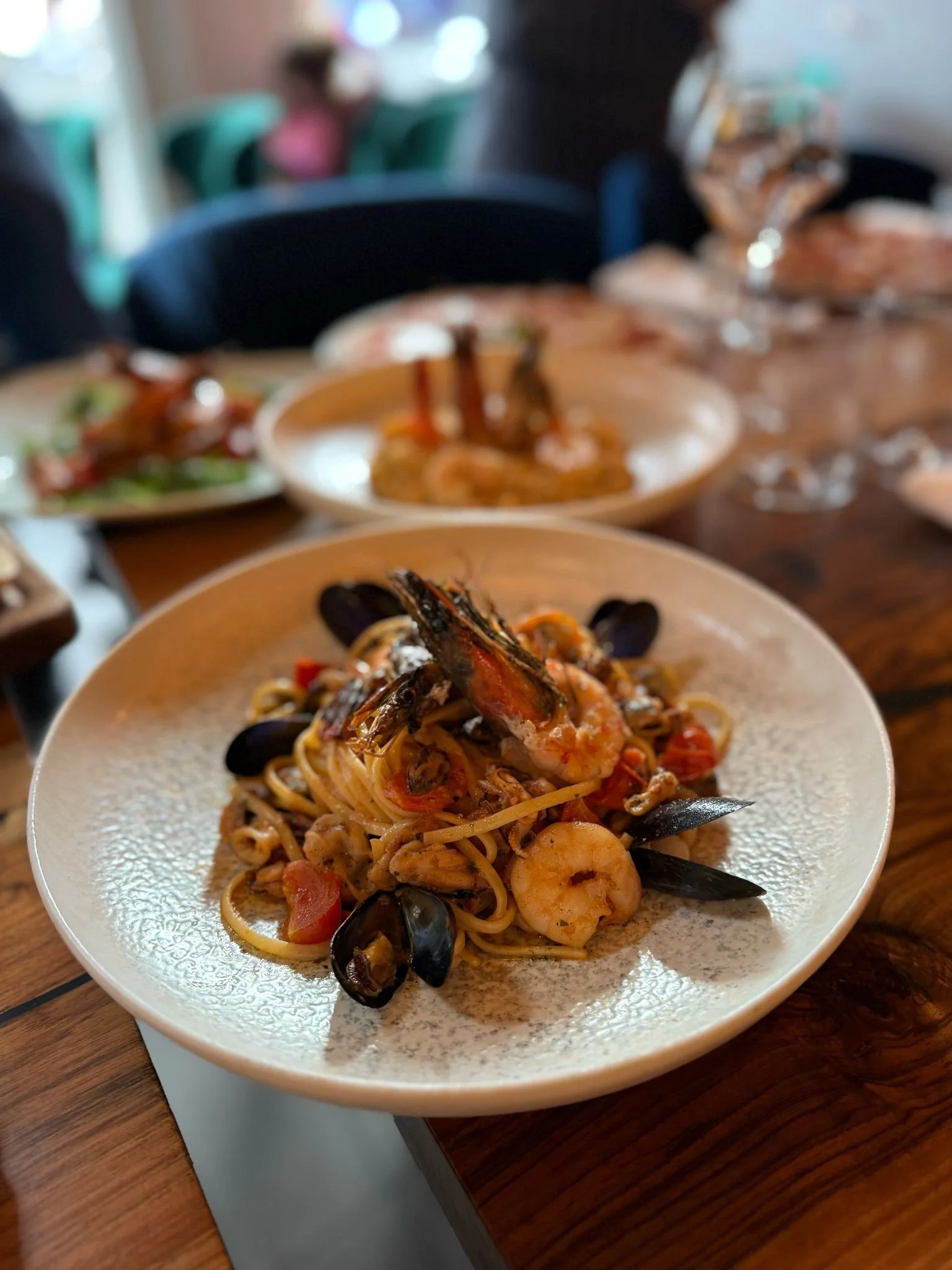 Seafood pasta with shrimp, mussels, and cherry tomatoes on a white plate