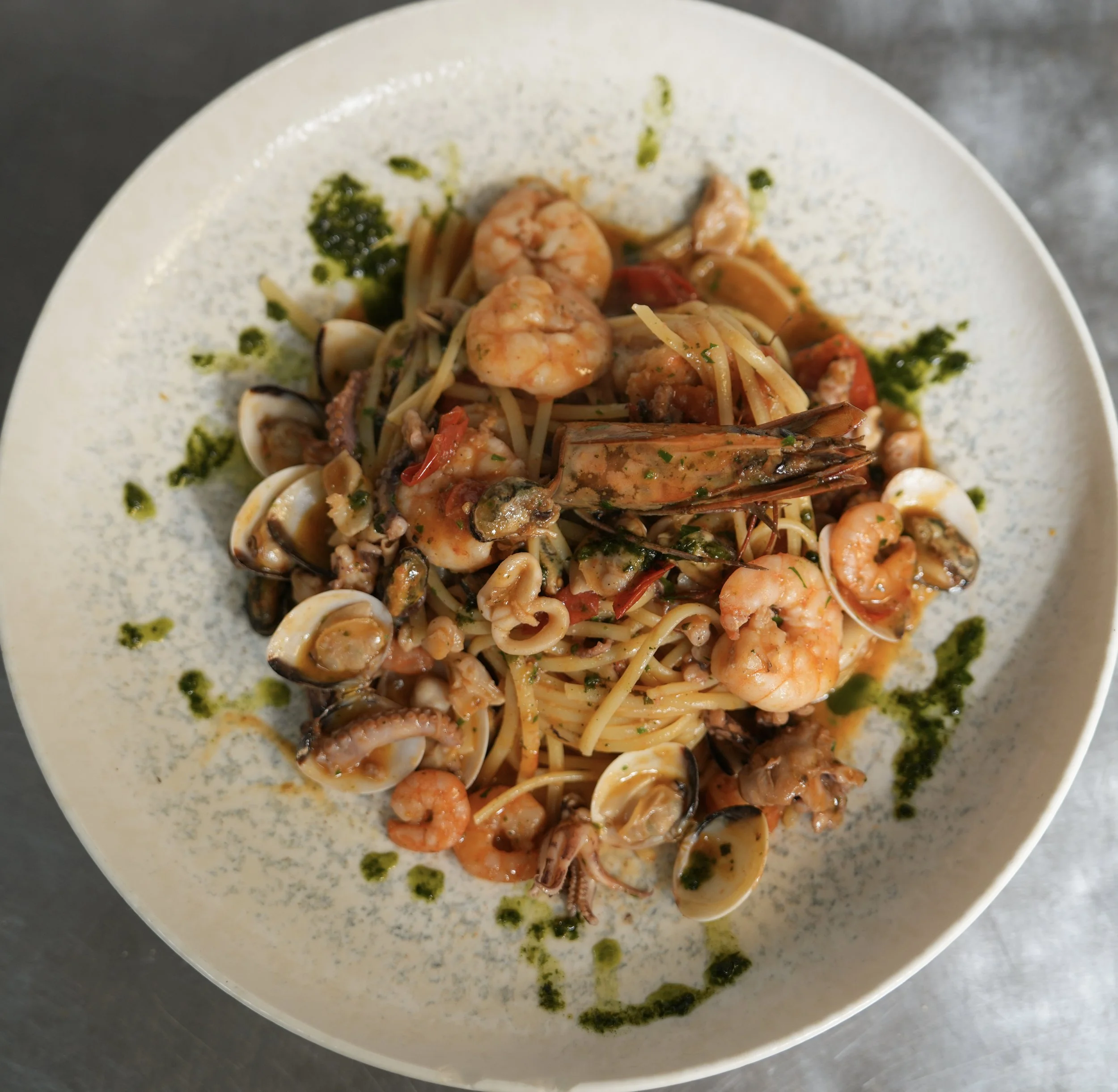 Seafood pasta with shrimp, clams, and squid in a creamy sauce, garnished with herbs.