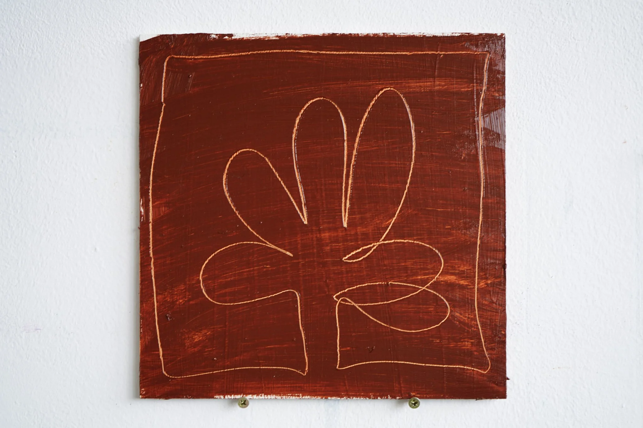 A red abstract artwork on a white wall featuring a simple line drawing with curved lines.