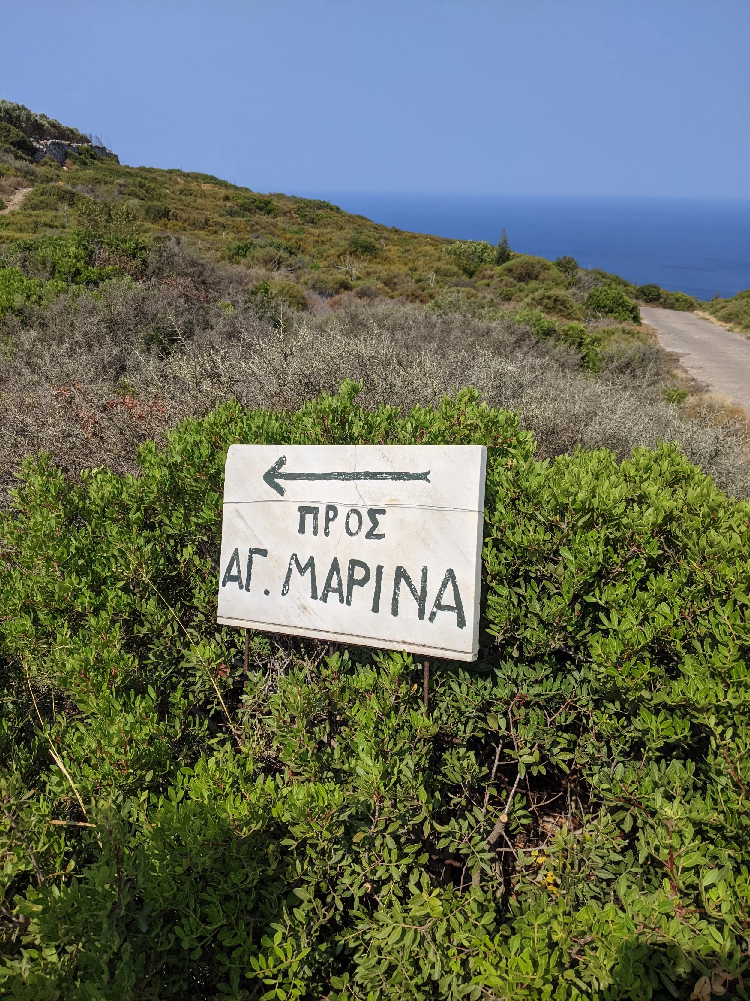 Hand-painted Greek sign on a hillside trail, guiding retreat-goers to new views and hidden gems