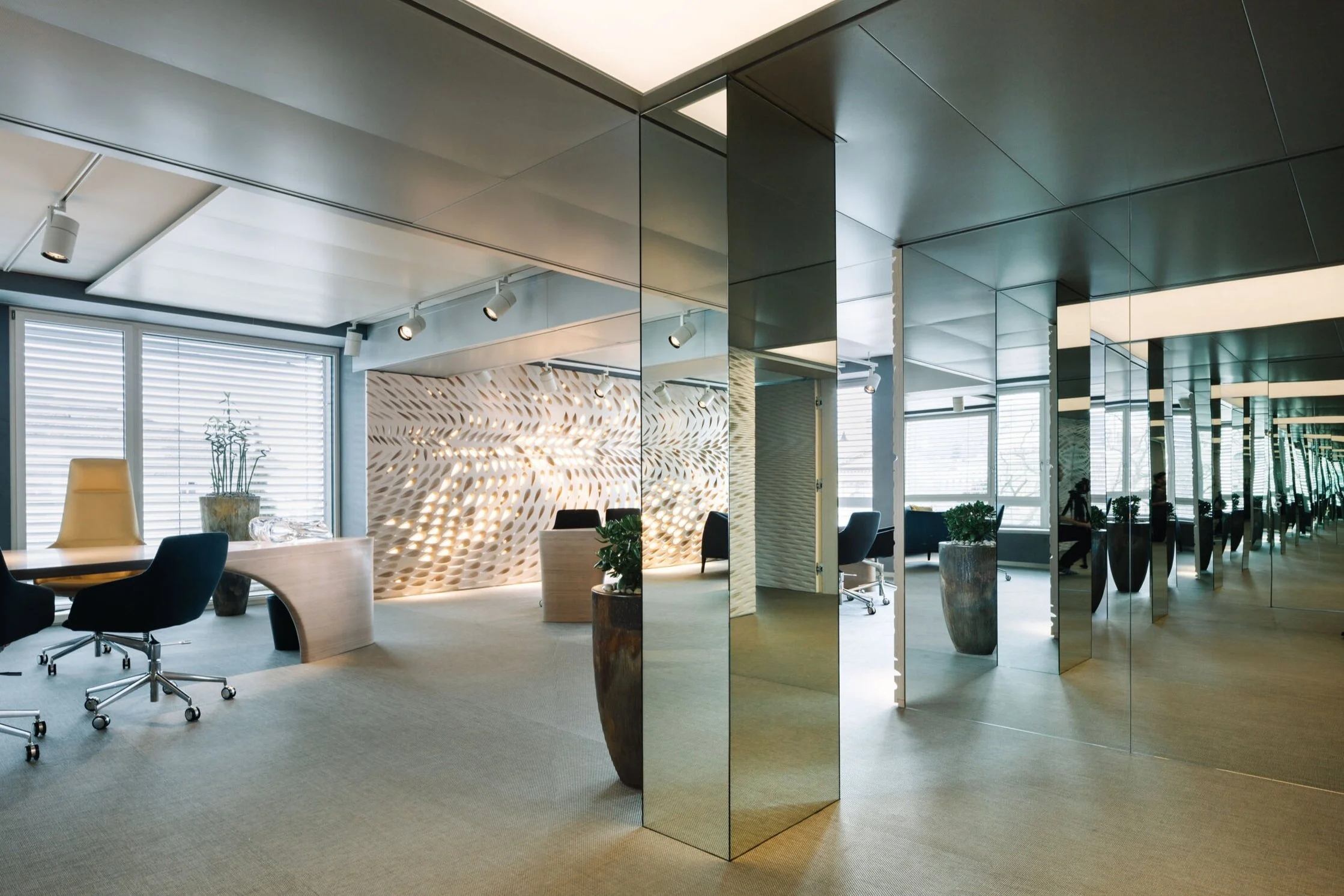 Modern office with large windows, mirrored walls, and contemporary furniture.