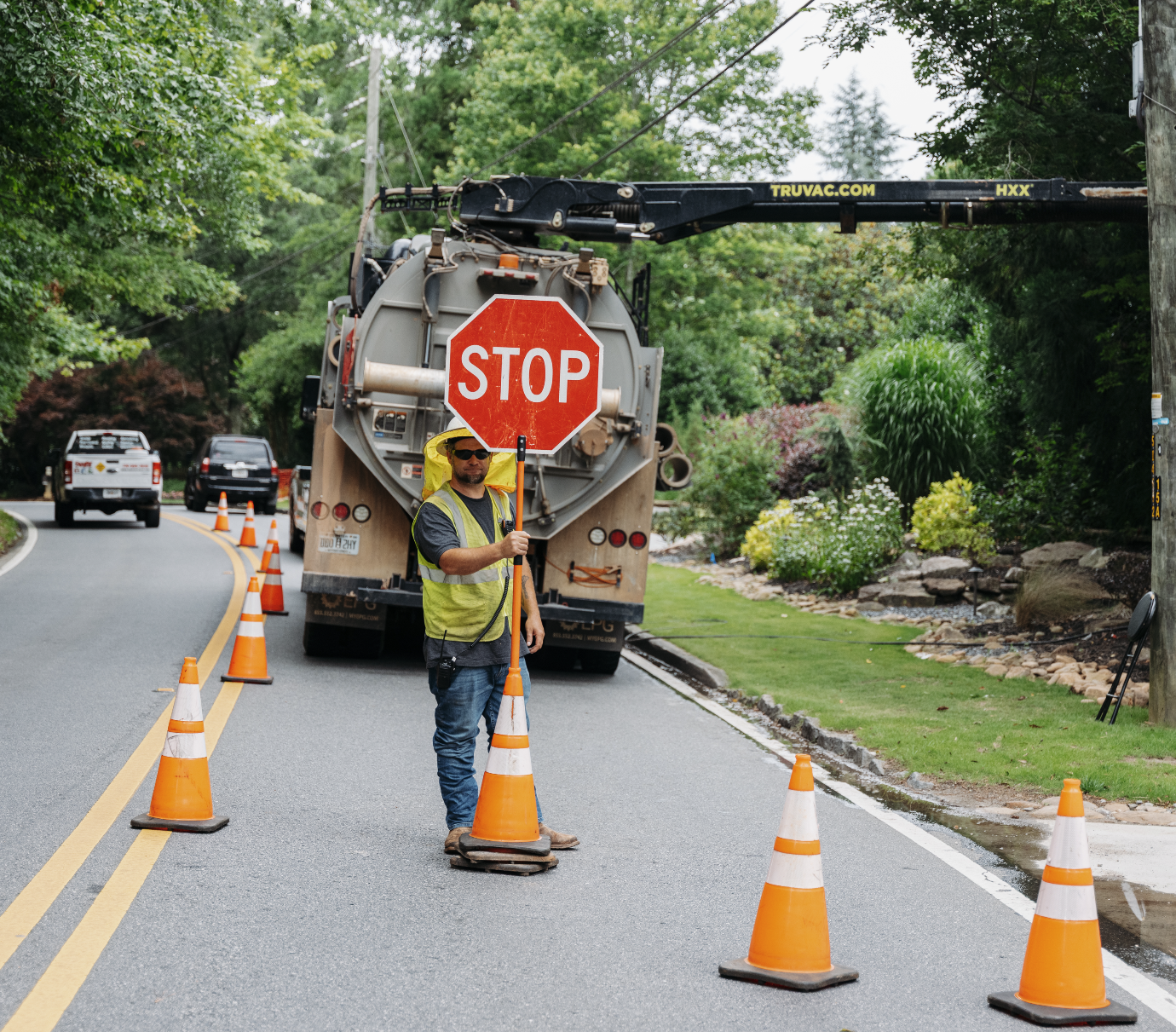 Roadwork with traffic cones, a closed sidewalk sign, and vehicles on the road.