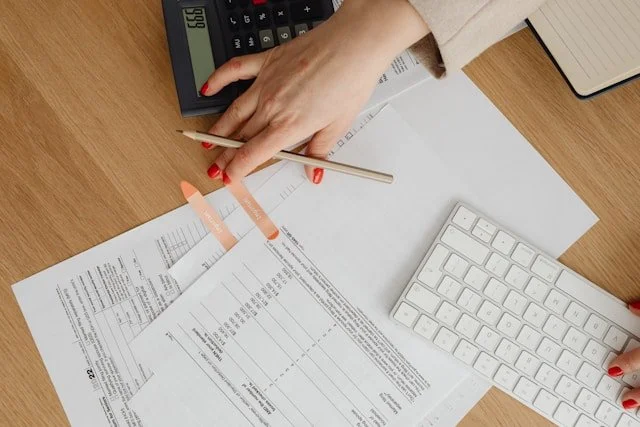 Person using calculator with documents and keyboard on a desk