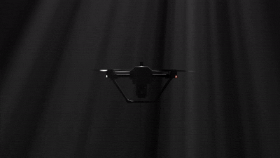 A drone suspended in midair against a dark backdrop.