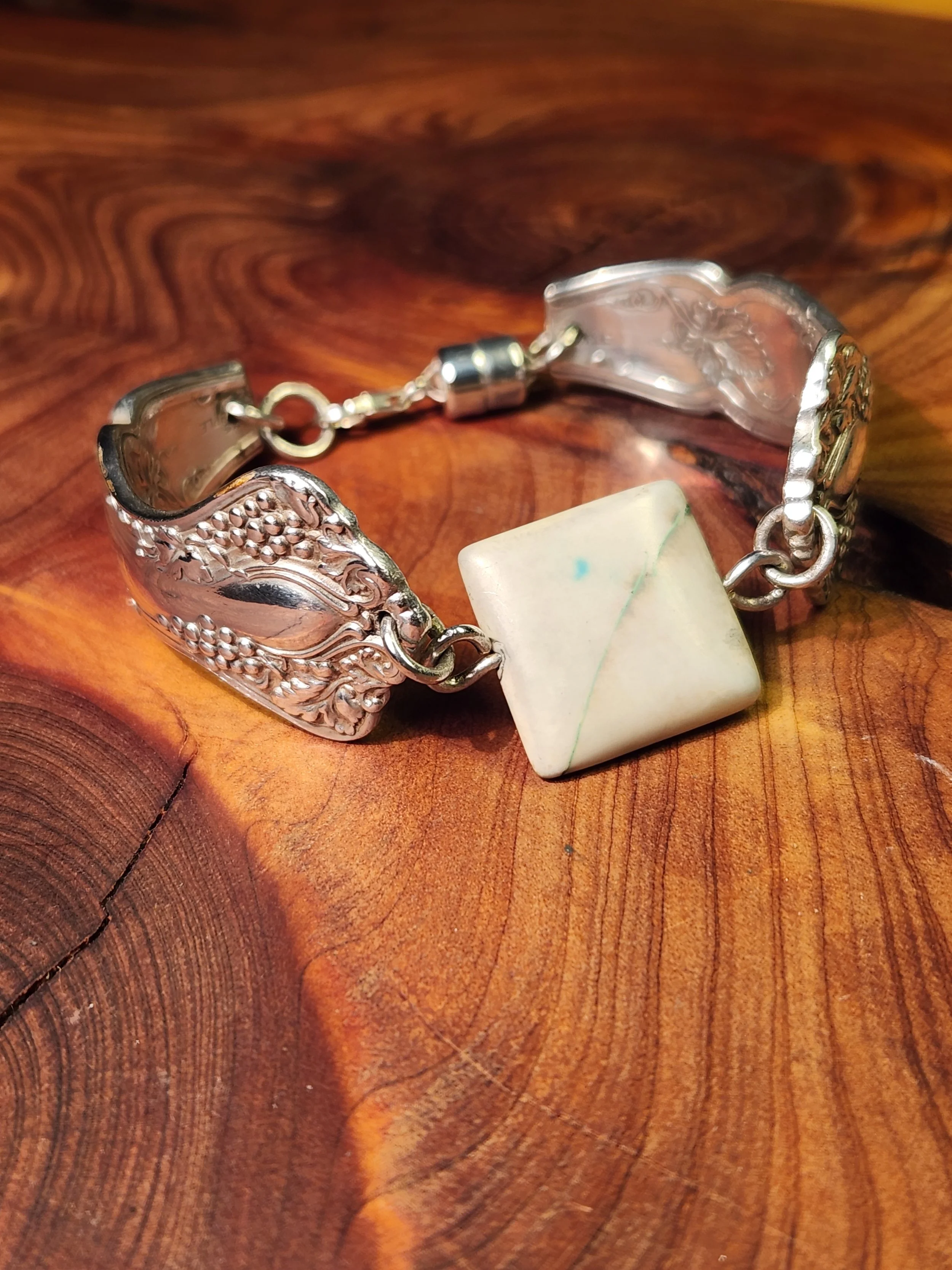 Silver bracelet with intricate floral design resting on a wooden surface