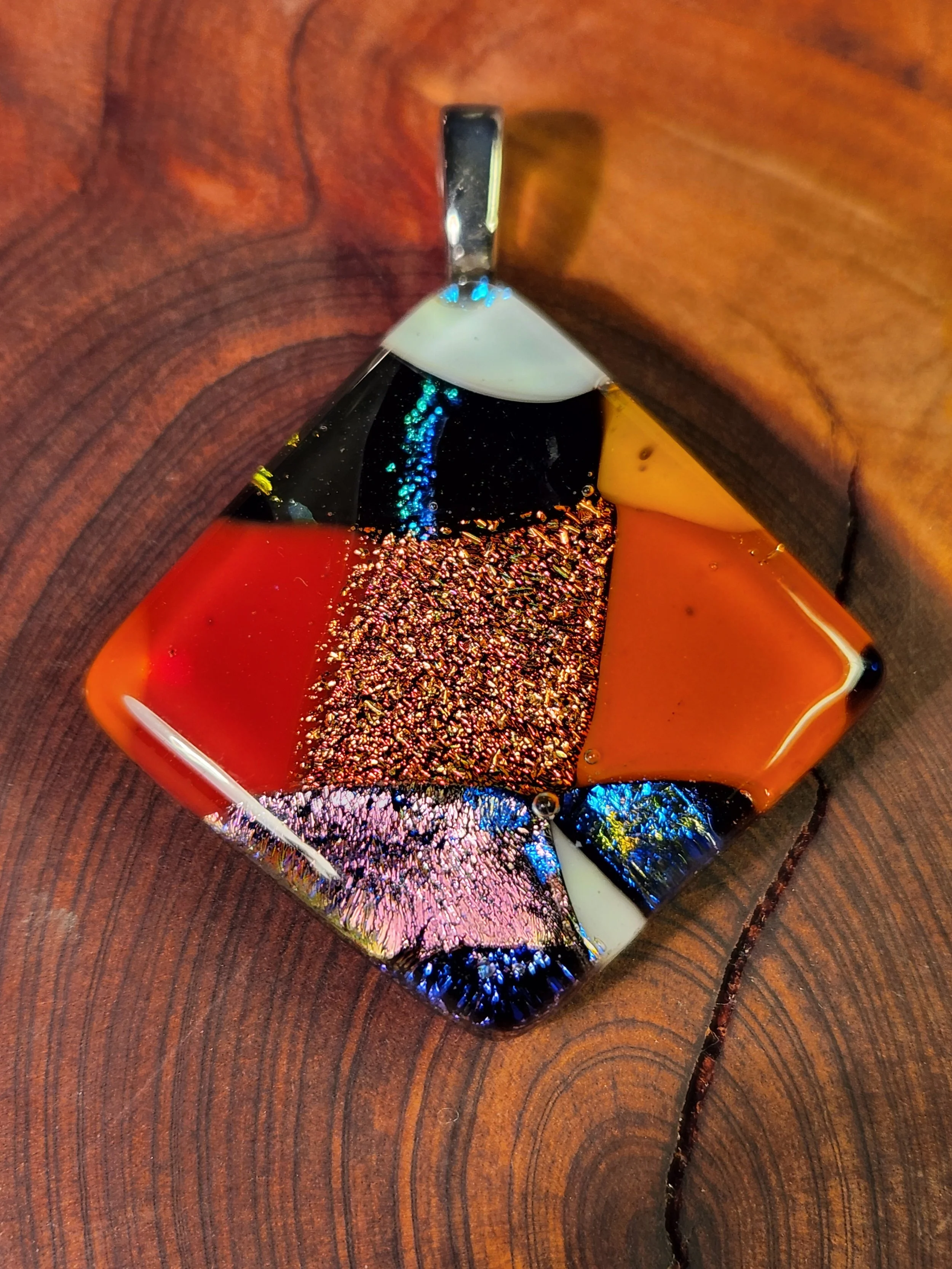 Close-up of a melting multicolored glass sculpture on a wooden surface.