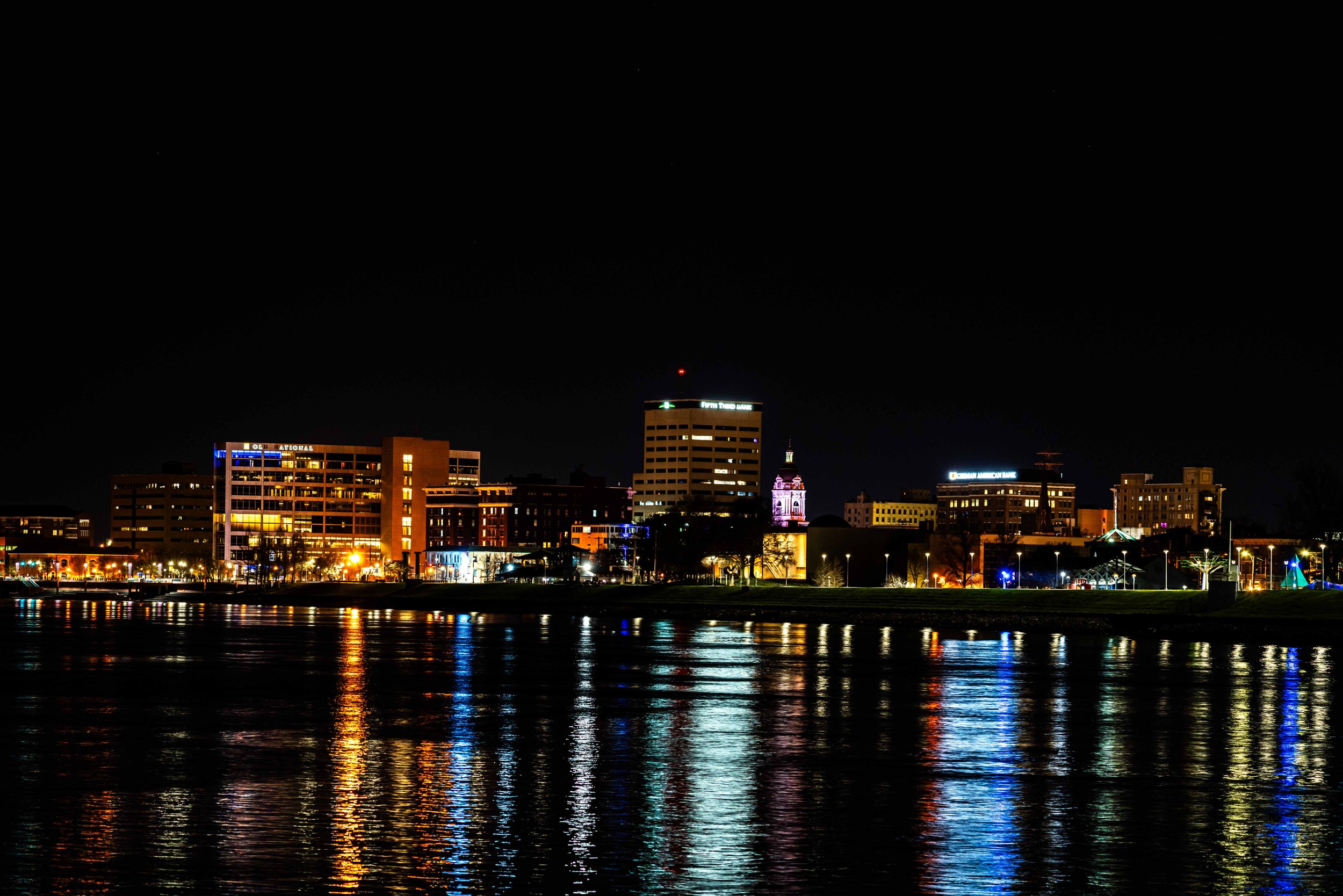 Nighttime cityscape with illuminated buildings reflecting on water