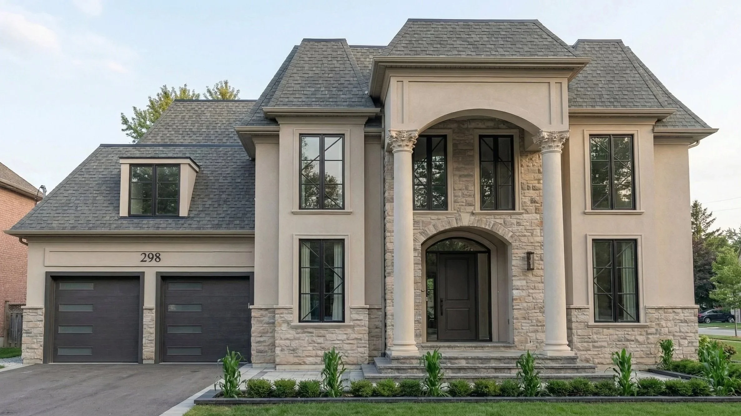 Modern French Provincial custom home exterior designed by Dar Architects Inc., featuring a luxury stone and stucco facade, grand arched entryway with Corinthian columns, mansard roof, and contemporary black-frame windows with a two-car garage.