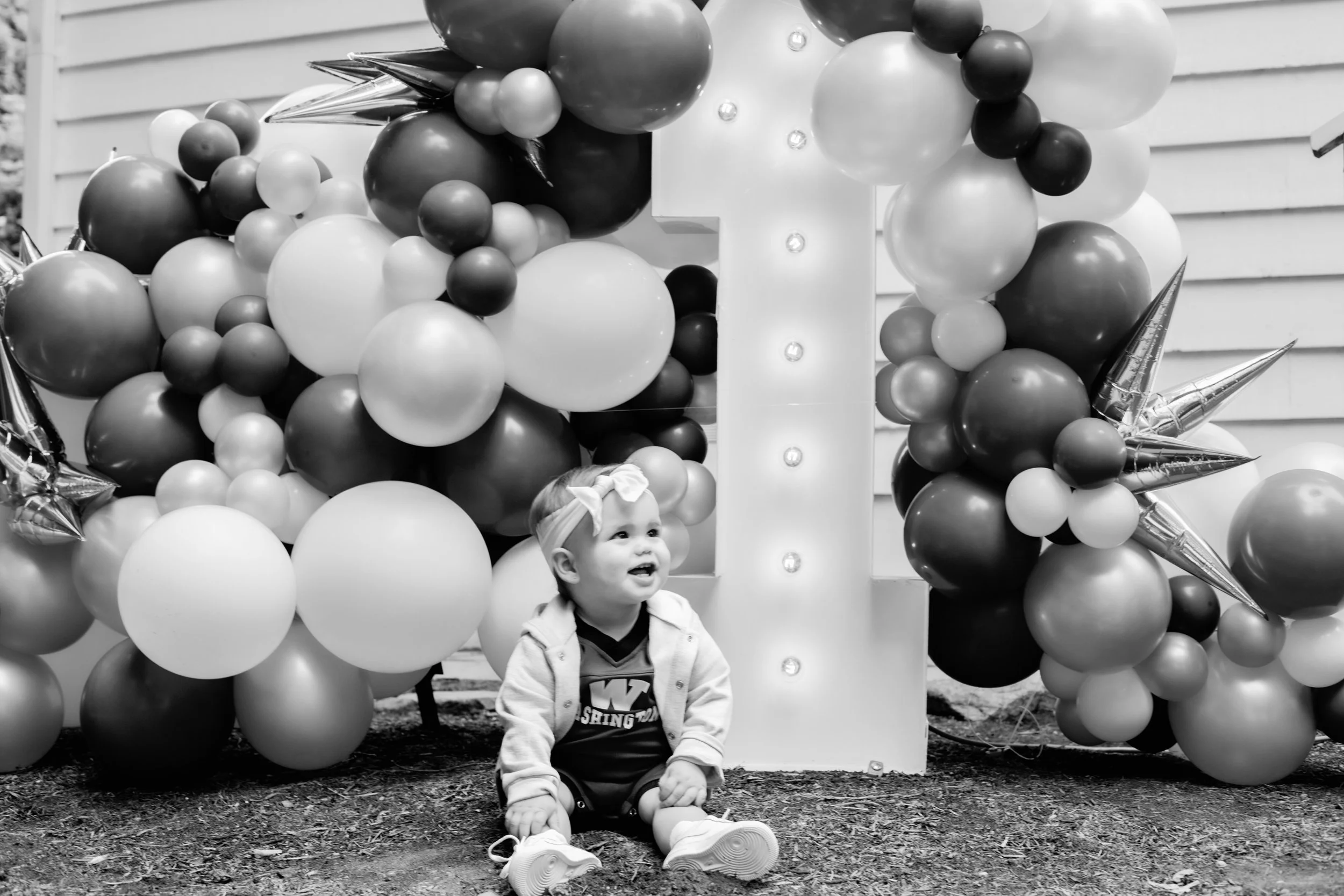 Child sitting in front of balloons.