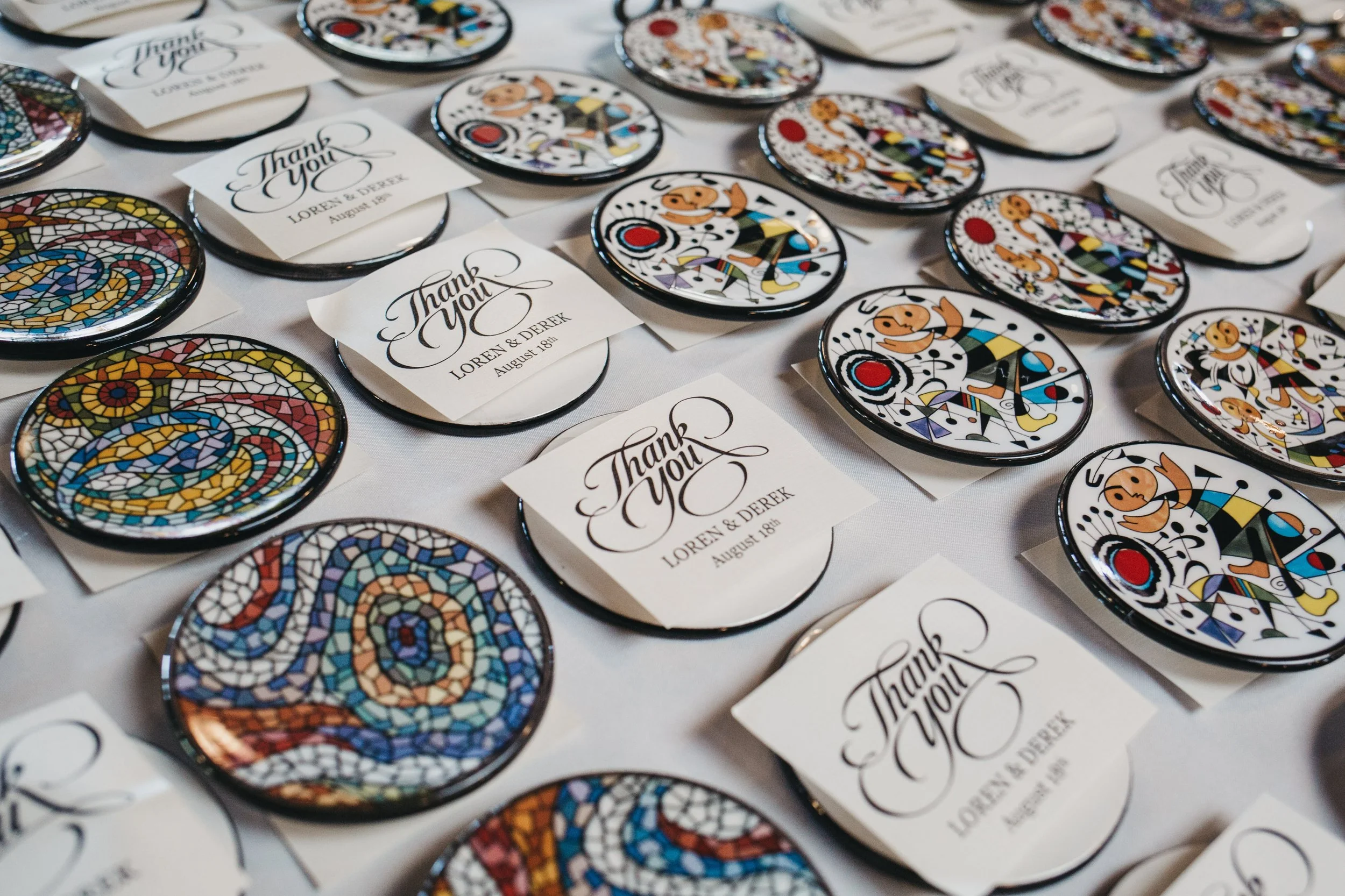 Mosaic-style buttons and thank you notes for a wedding, dinnerware, with a white tablecloth background.