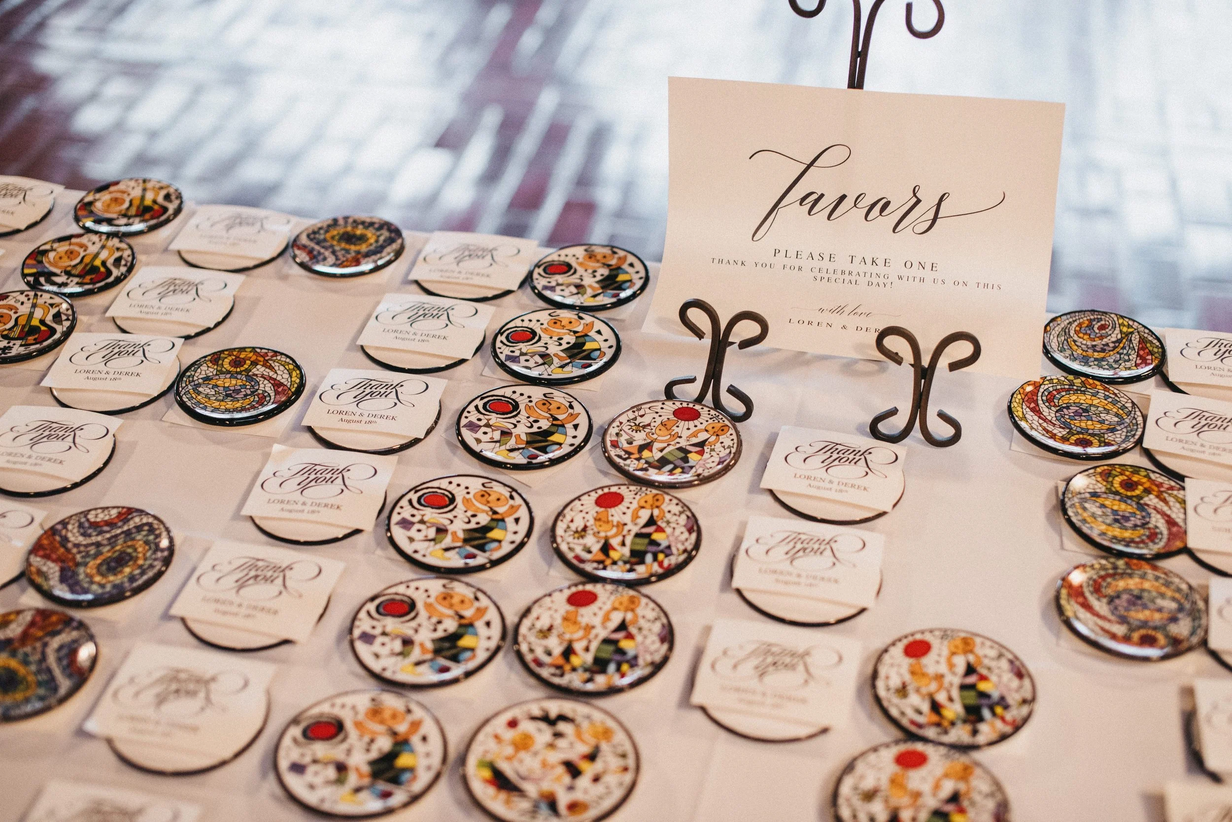 Table setting with colorful round badges and thank you notes at a wedding reception, with a table sign that says "Favorites"