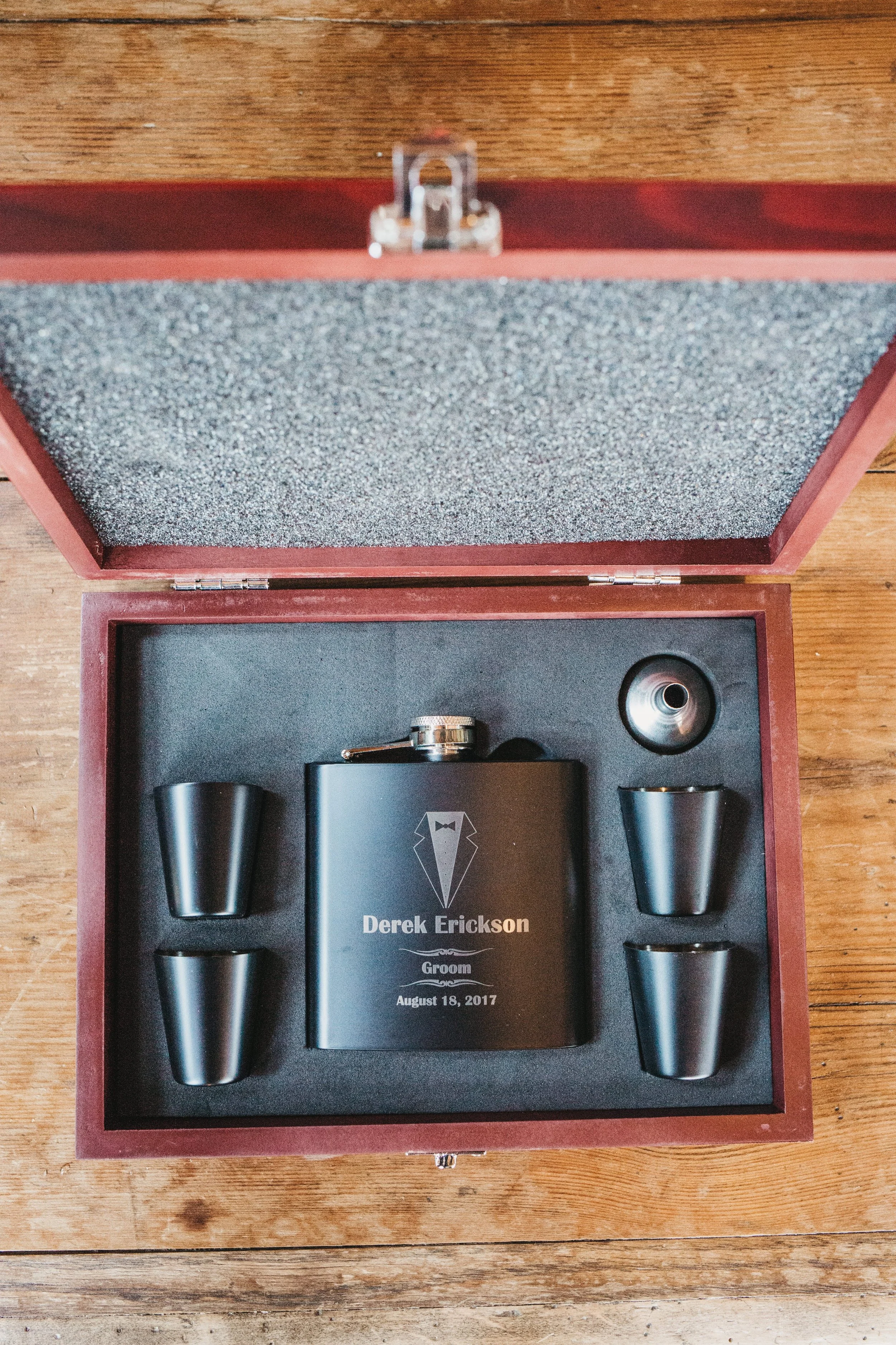 Custom engraved flask with four shot glasses in an open wooden box for a groom, dated August 18, 2017.