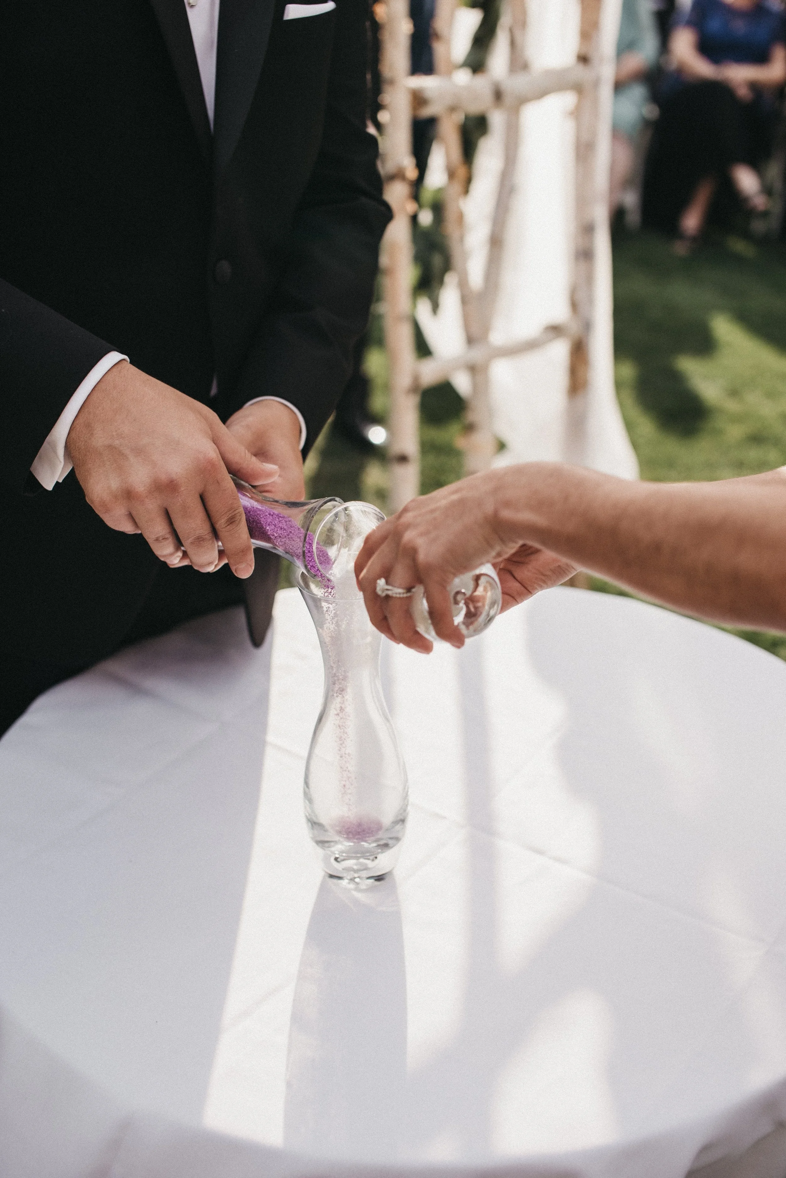 A couple pouring pink sand into a vase during a wedding ceremony.