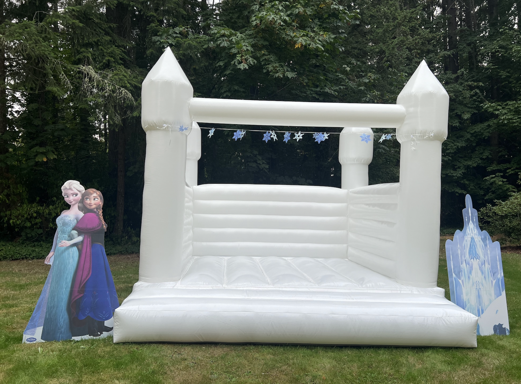 White inflatable castle for children with snowflake decorations, featuring characters Elsa and Anna from Frozen on either side.