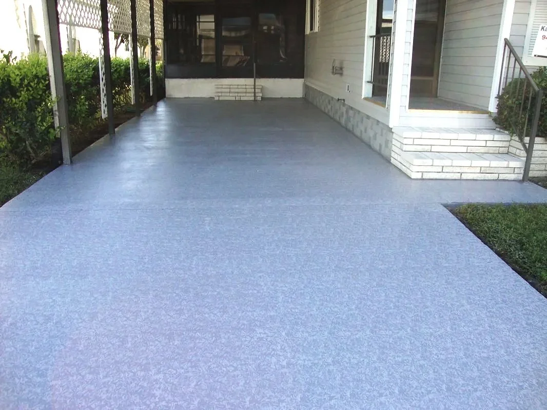 Freshly painted concrete porch with a blue-gray finish, attached to a house with white siding and brick steps, surrounded by a small green lawn and shrubs.