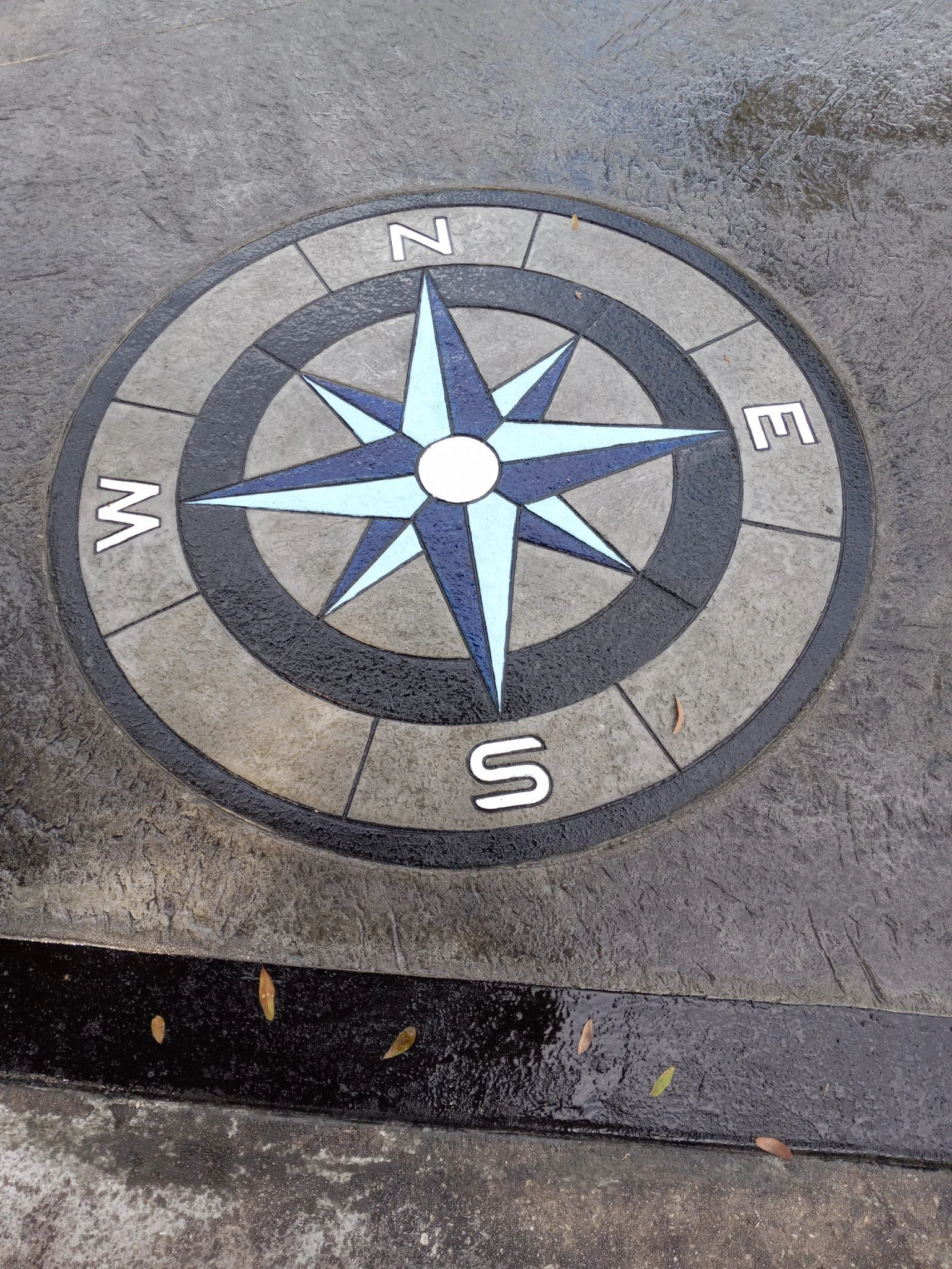 Decorative compass rose on the ground with North, East, South, and West labels.