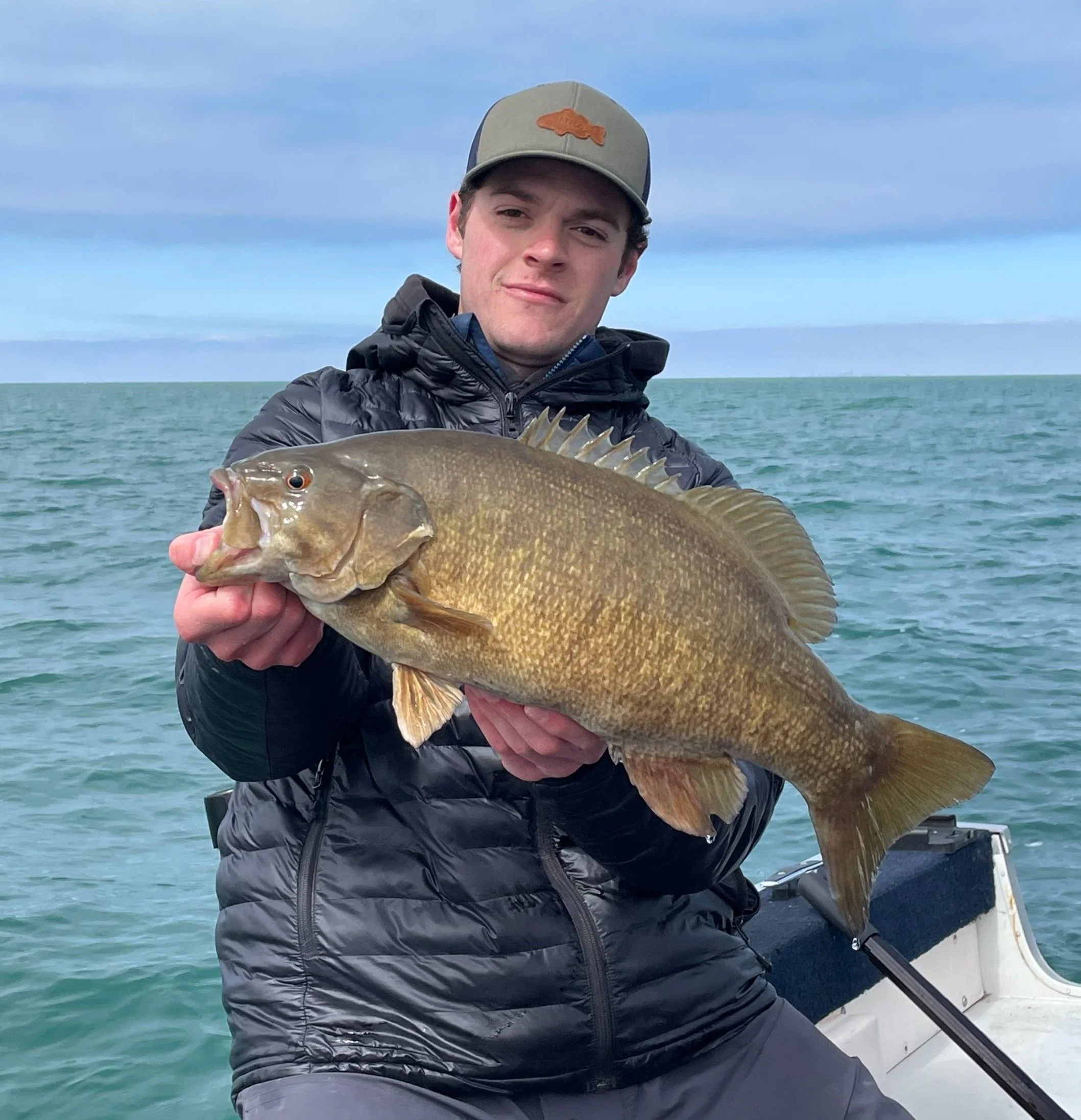 Person holding a large fish on a boat with ocean in the background
