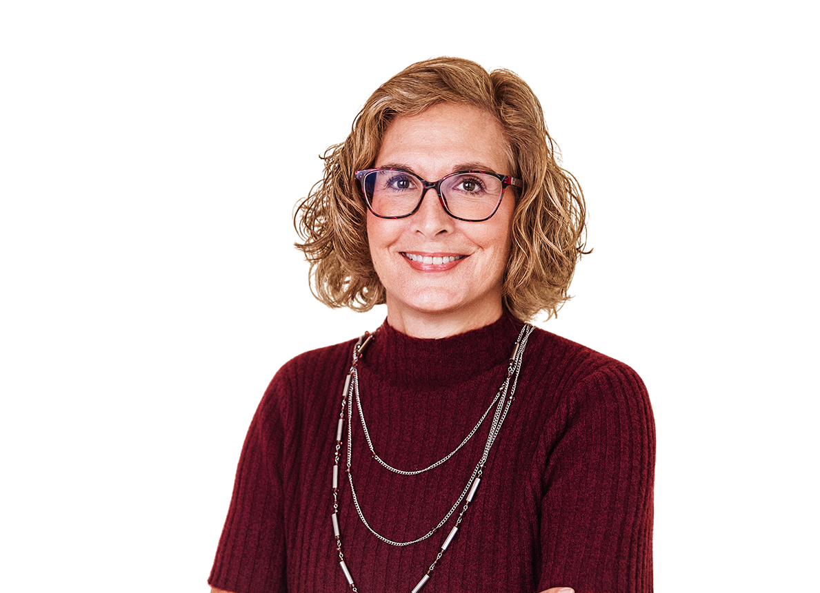 A woman with curly hair, wearing glasses and a maroon sweater, smiles at the camera.