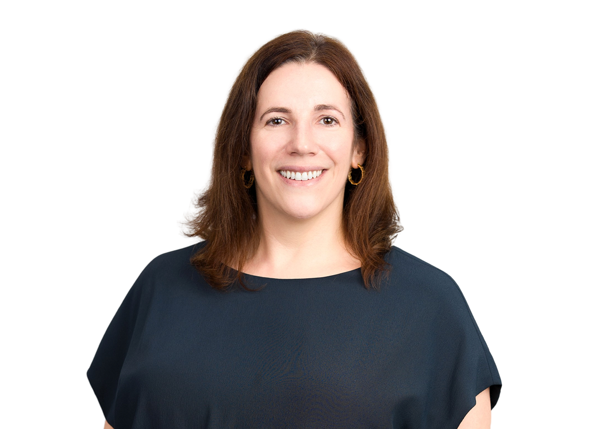 A woman with shoulder-length brown hair, wearing a navy blue top and gold hoop earrings, smiling at the camera.