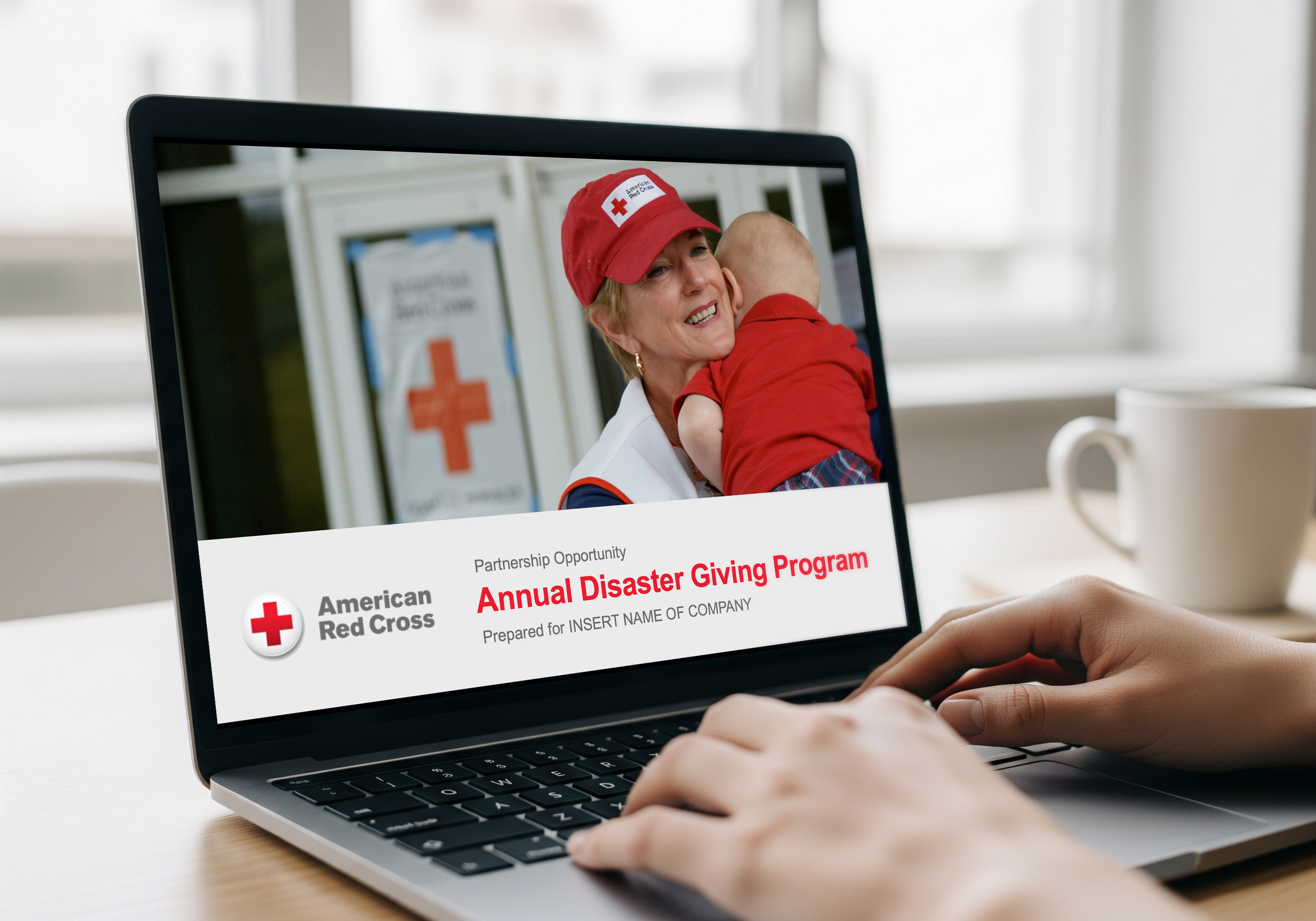 Laptop displaying a webpage for the American Red Cross Annual Disaster Giving Program, with a woman holding a child. The screen shows a woman in a Red Cross cap and logo in front of Red Cross banners.